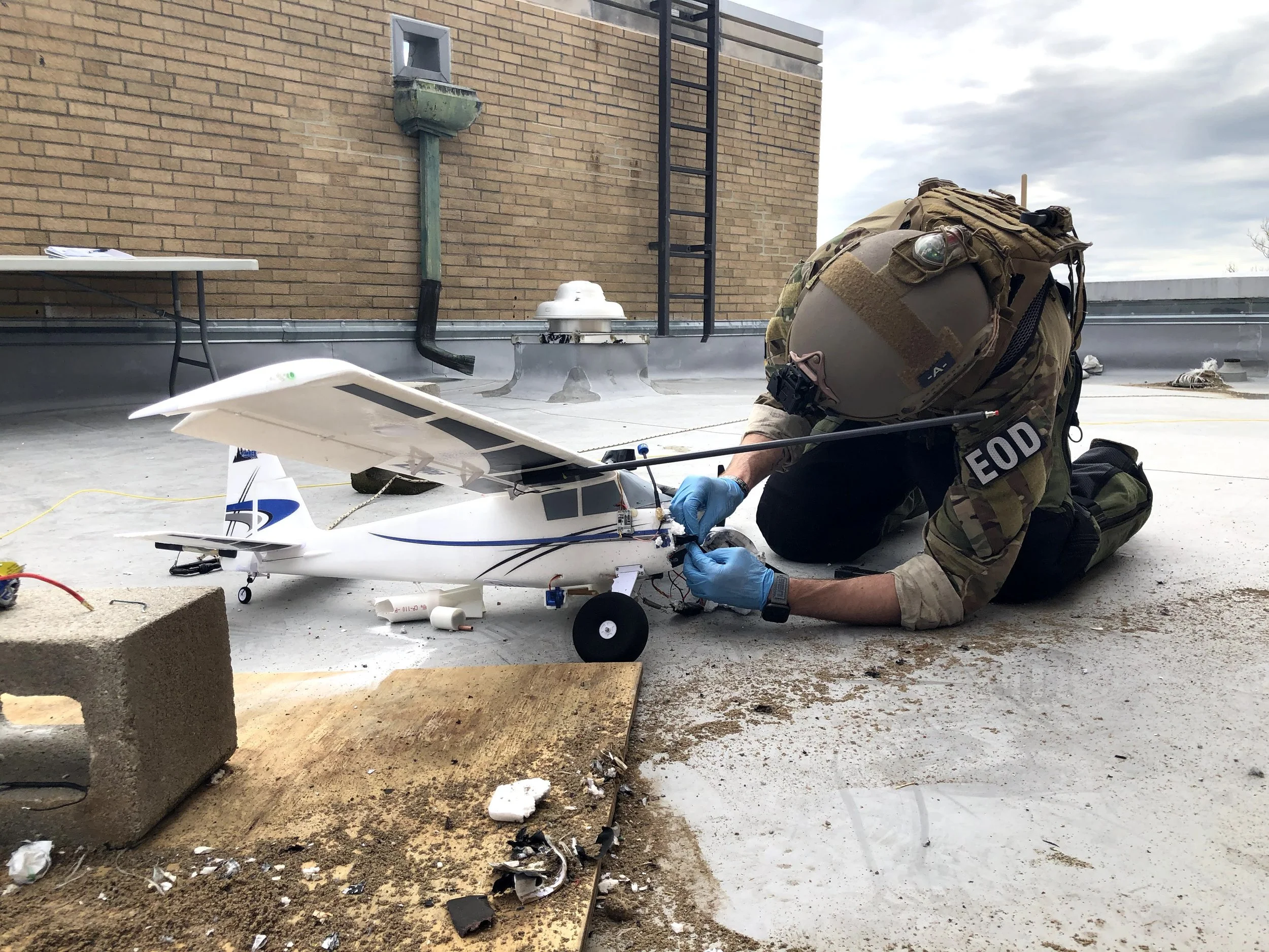 An Explosive Ordnance Disposal Technician examines a weaponized grounded drone during a training exercise.