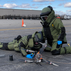 Bomb squad technician assessing potential explosive hazard on grounded drone