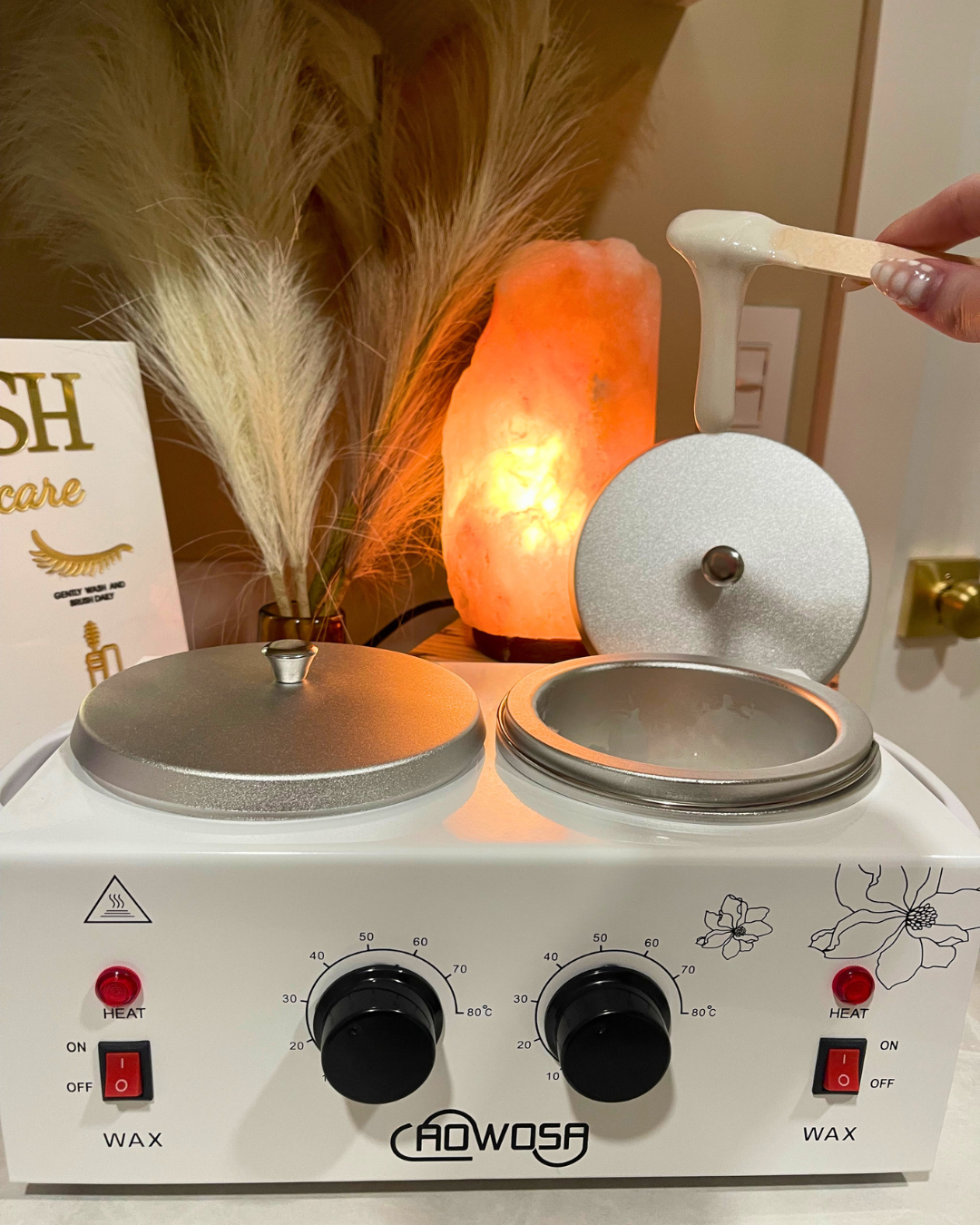 Wax pot with esthetician holding wax stick dripping wax.