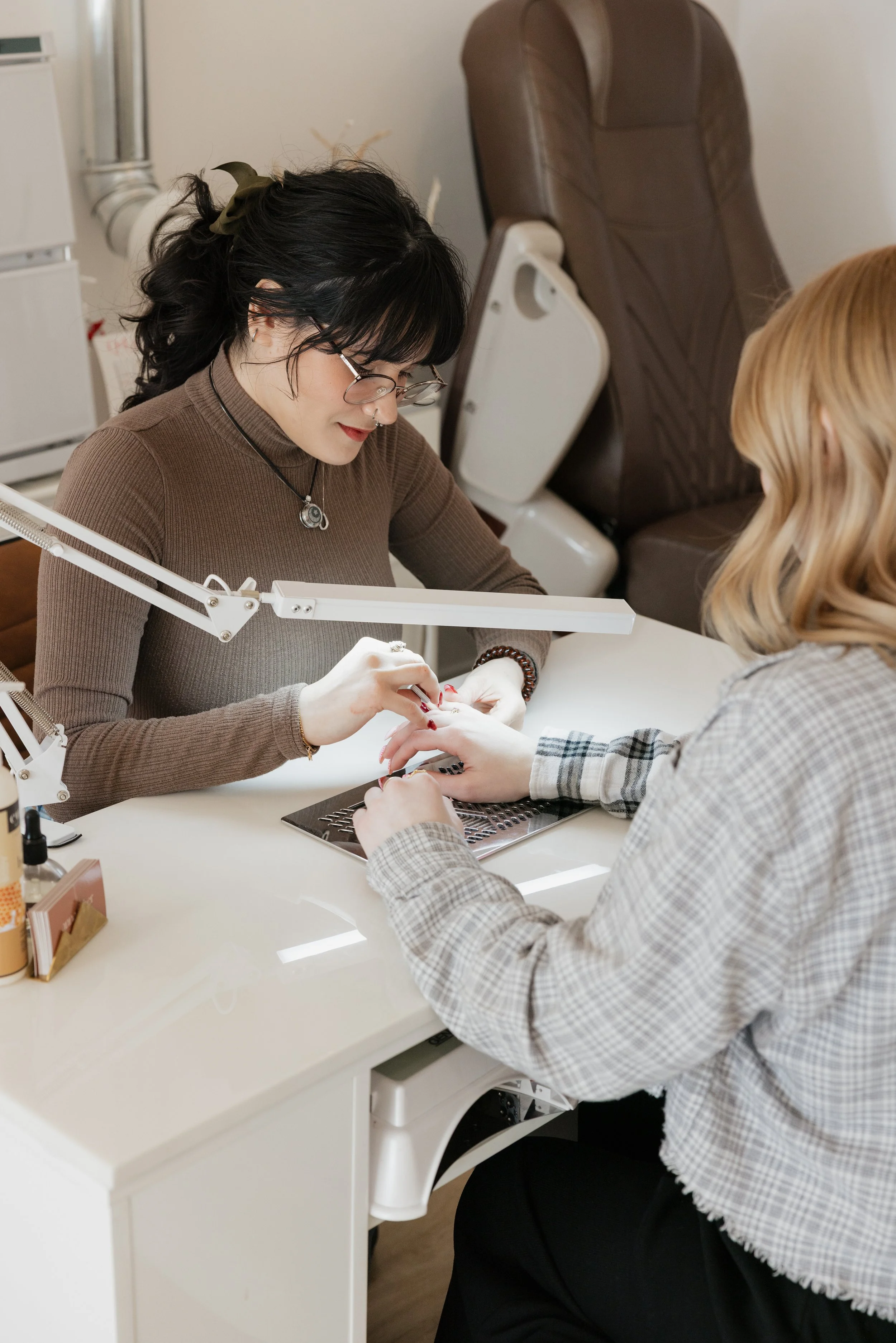 Nail salon technician painting a client's nails during a manicure session at a modern nail salon.