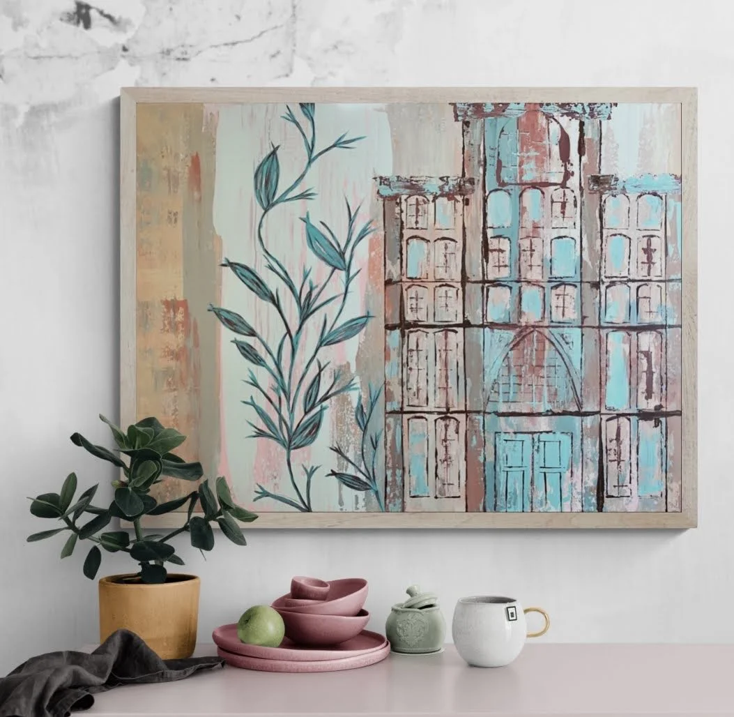 Decorative painting of a building with blue and pink tones hanging on a white wall above a surface with a potted plant and ceramic dishware.