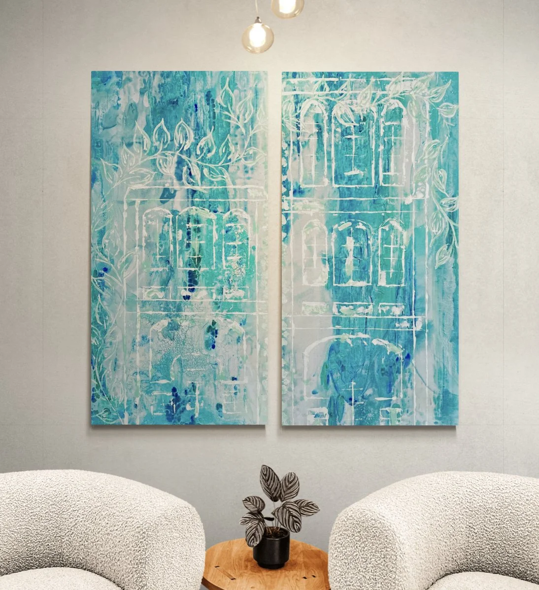 Two abstract paintings using blue and white colors hang on a white wall, depicting a building with windows and surrounded by leaves, with a flower pot with a leafy plant and two white textured chairs beneath.