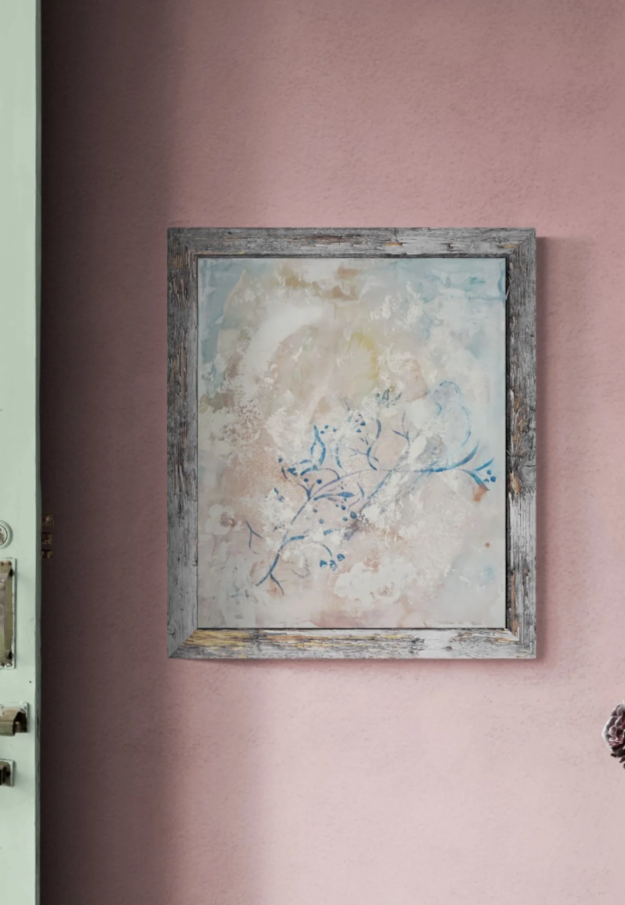 Framed abstract painting with floral design hanging on pink textured wall.