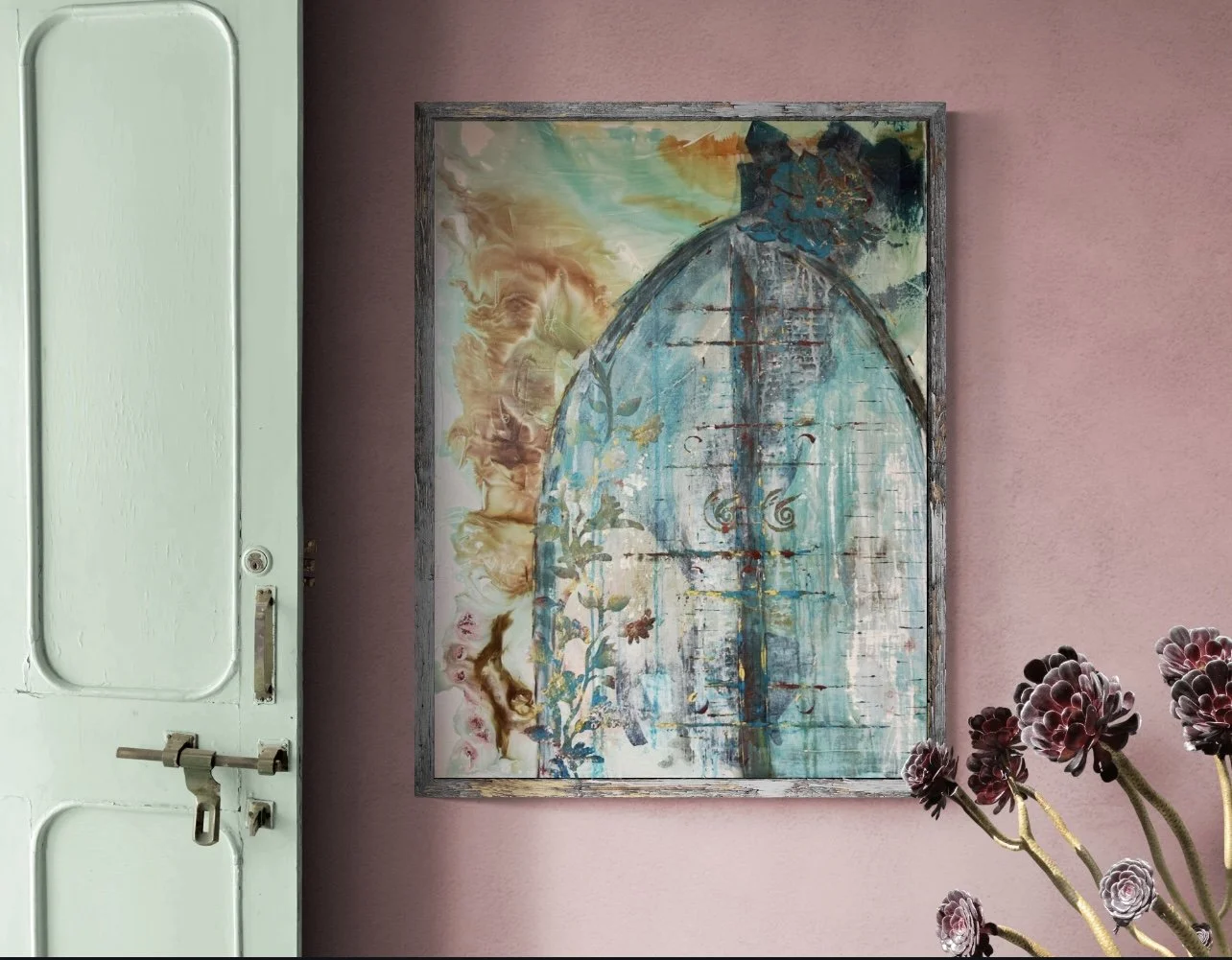 A colorful abstract painting with blue, orange, and green hues hangs on a pink wall next to a white vintage door with a metal latch. There are dark purple flowers with green stems in the foreground.