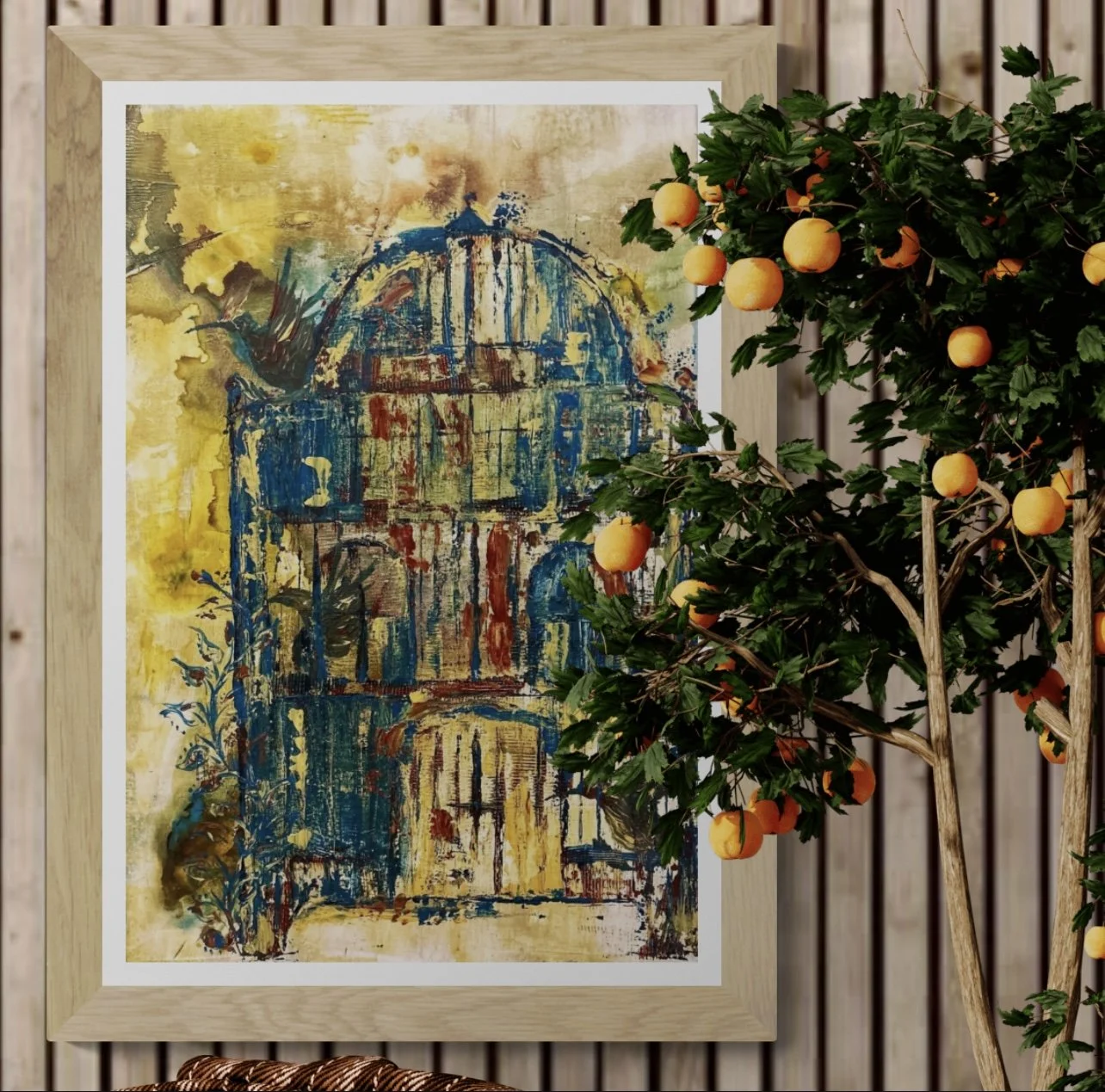 A colorful watercolor painting of a domed historic building, framed and leaning against a wall, with a lush orange tree with ripe fruit in front of it.