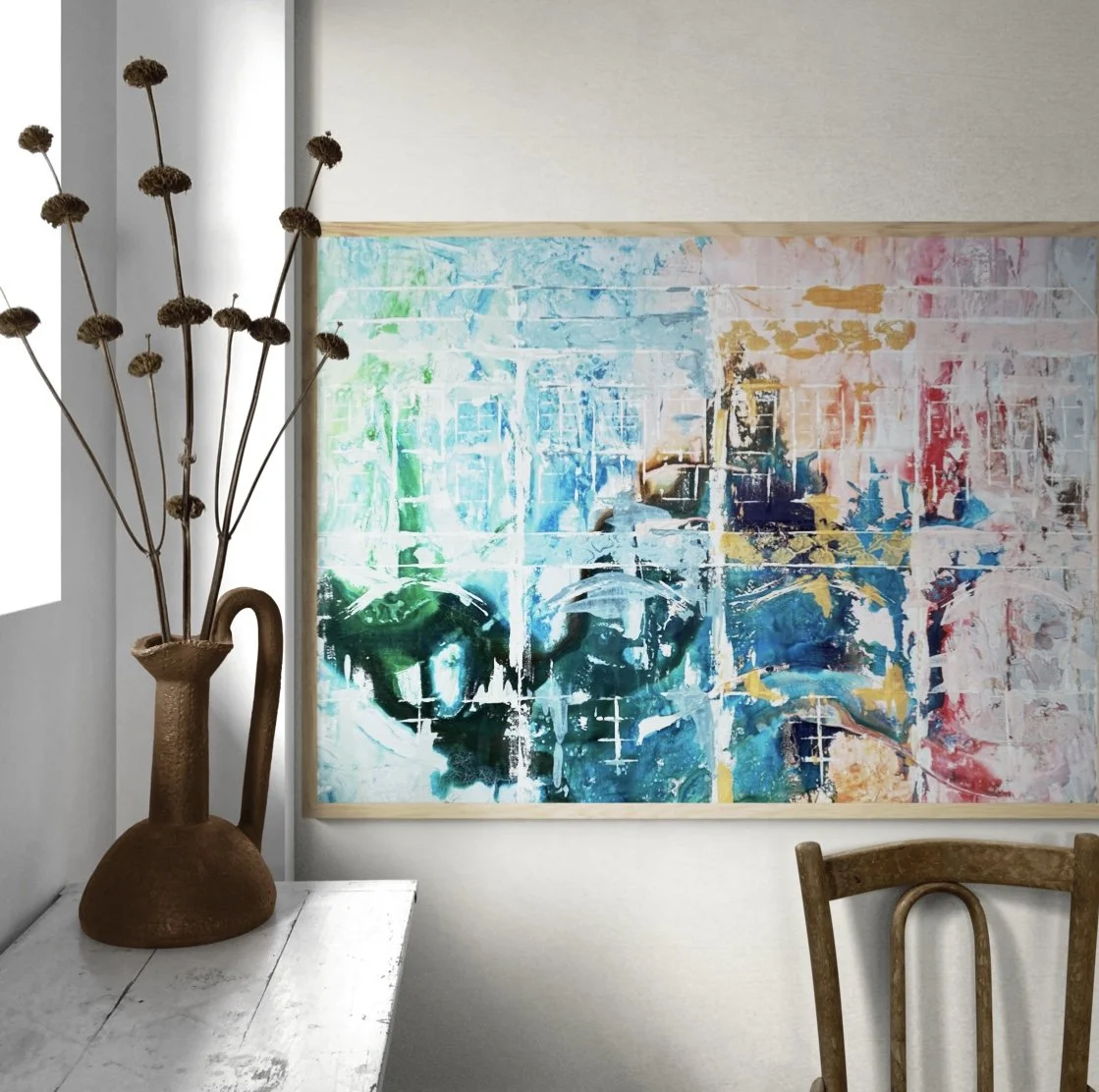 Decorative bouquet of dried flowers in a rustic, brown pitcher next to an abstract colorful painting on a white wall, with part of a wooden chair visible in a cozy room.