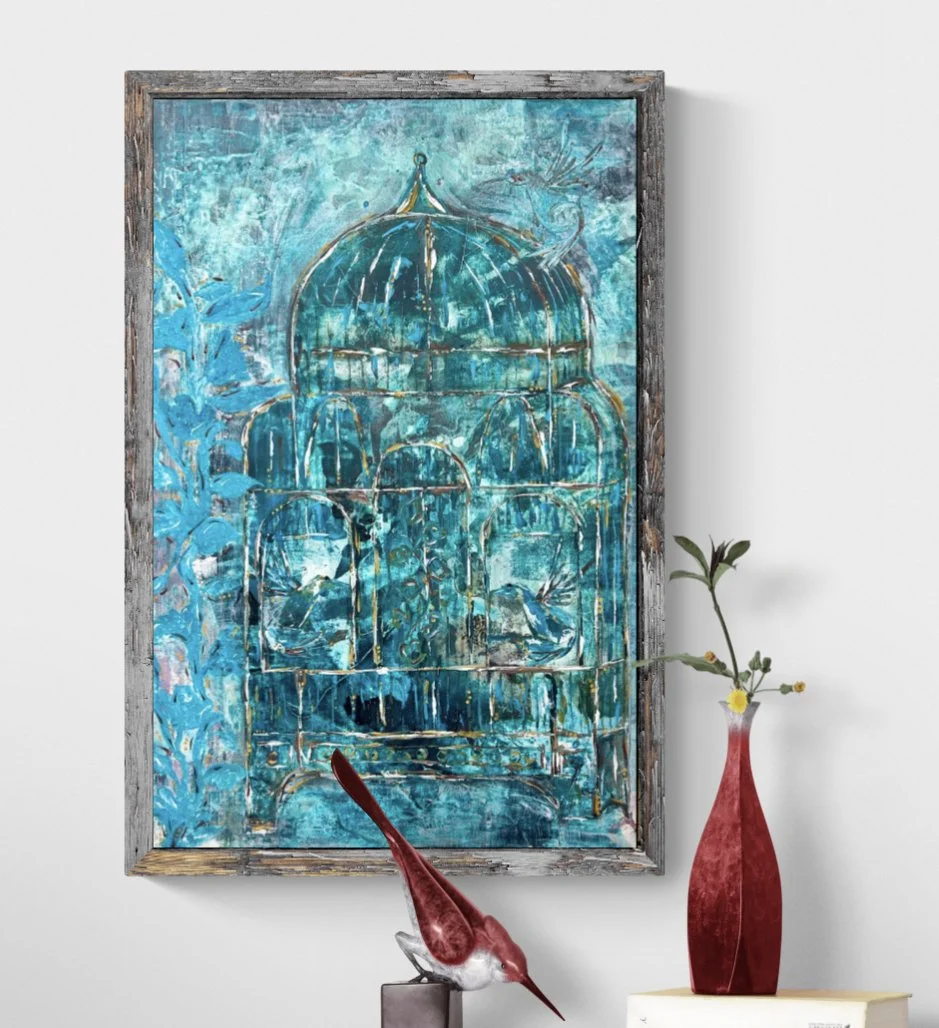 A painting of a birdcage with birds, in shades of blue and teal, hanging on a wall. Beside it is a red vase with a single branch and small yellow flowers, and a red and white bird figurine on a stand.