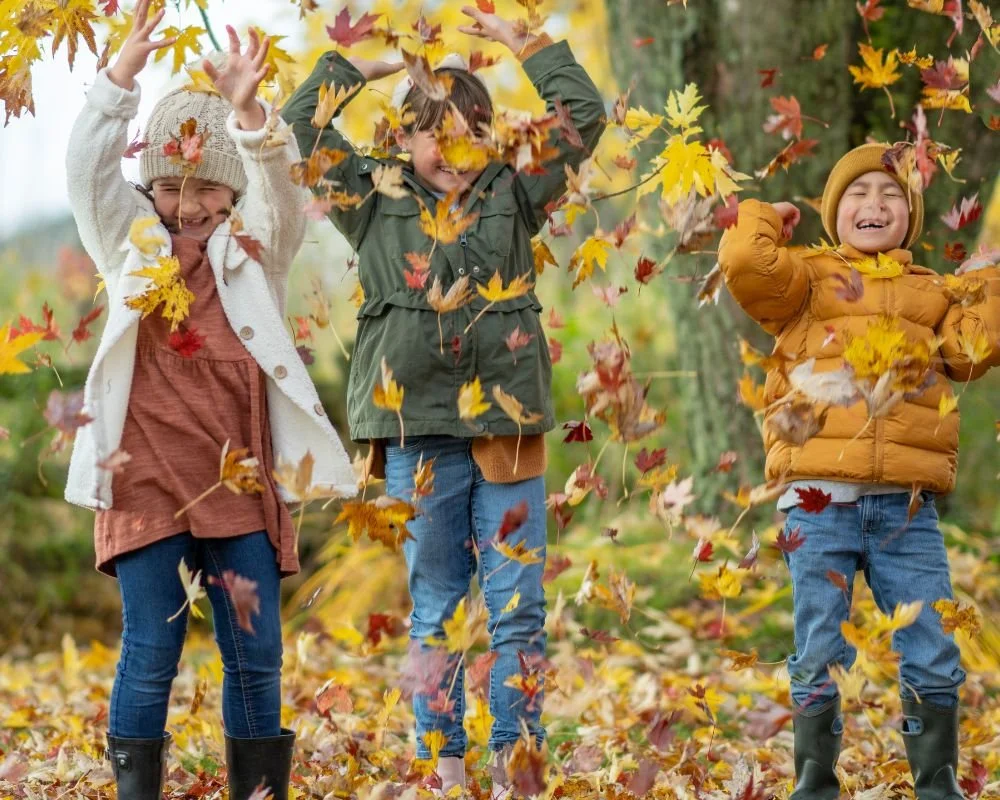 children throwing leaves in fall