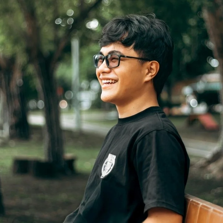Young man smiling outdoors in park.
