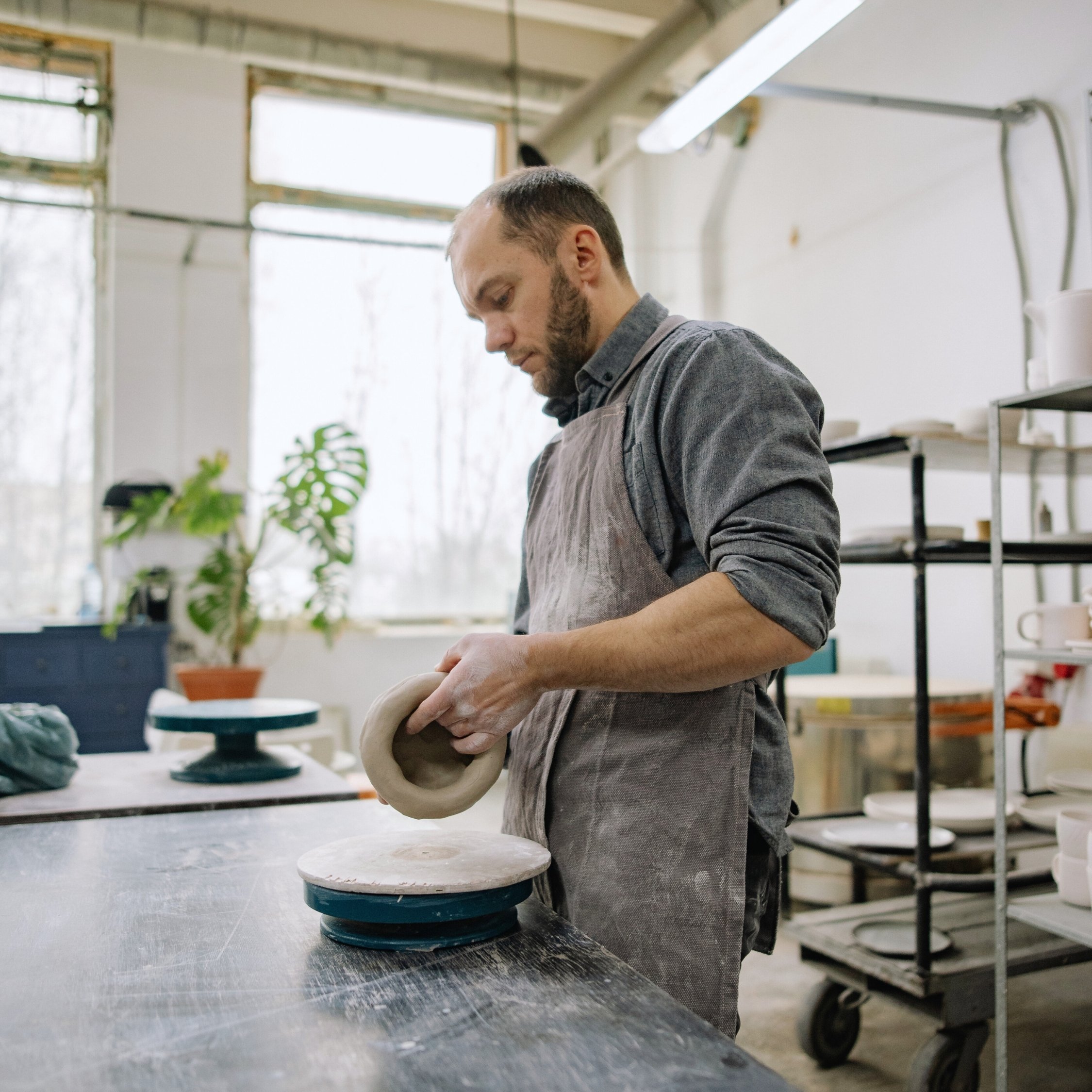 Man shaping clay in pottery studio.