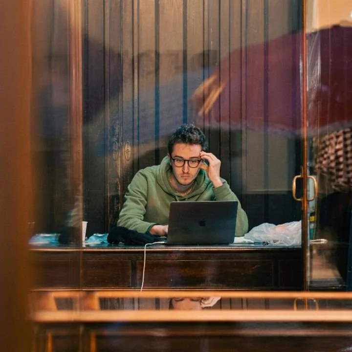 Man working on laptop during online therapy or mental health support session.