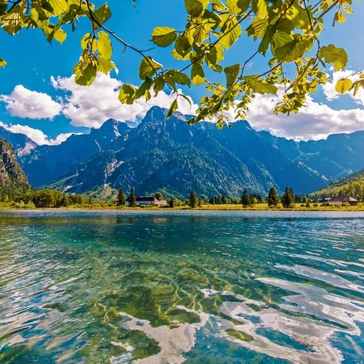 Clear lake with mountain landscape under blue sky.