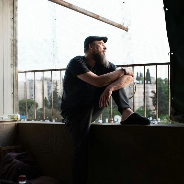 Man sitting thoughtfully by window during emotional reflection.