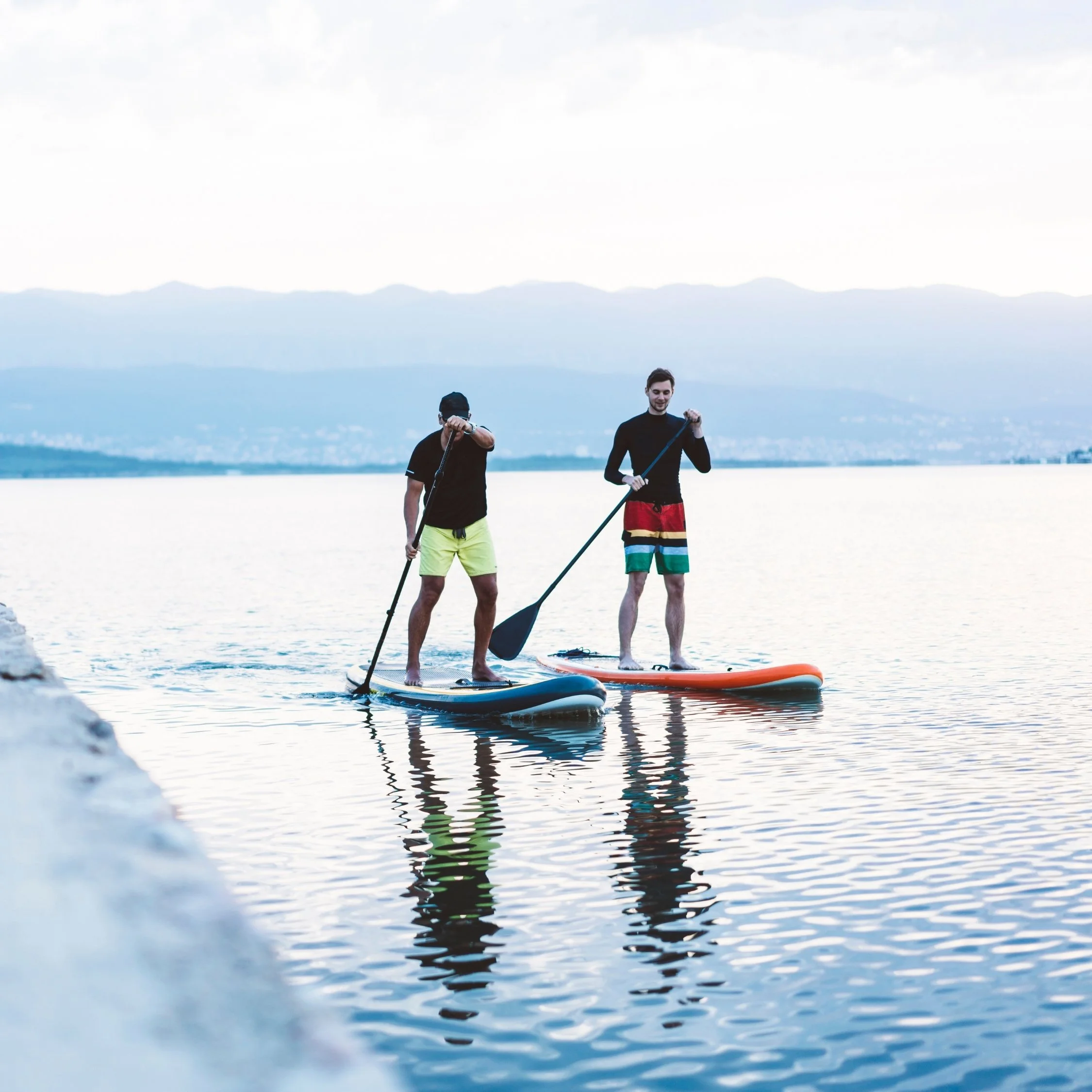 Father and son paddleboarding on calm water.