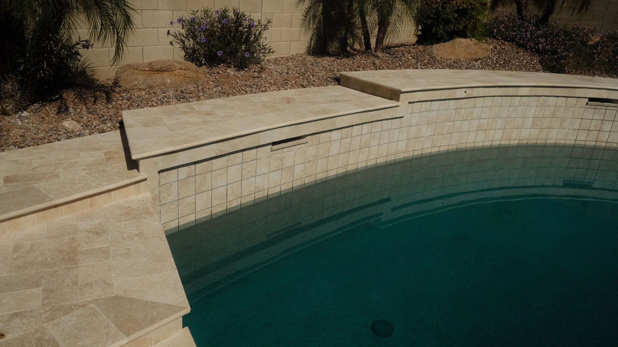 Close-up of travertine steps leading into a renovated pool in Phoenix, Arizona.