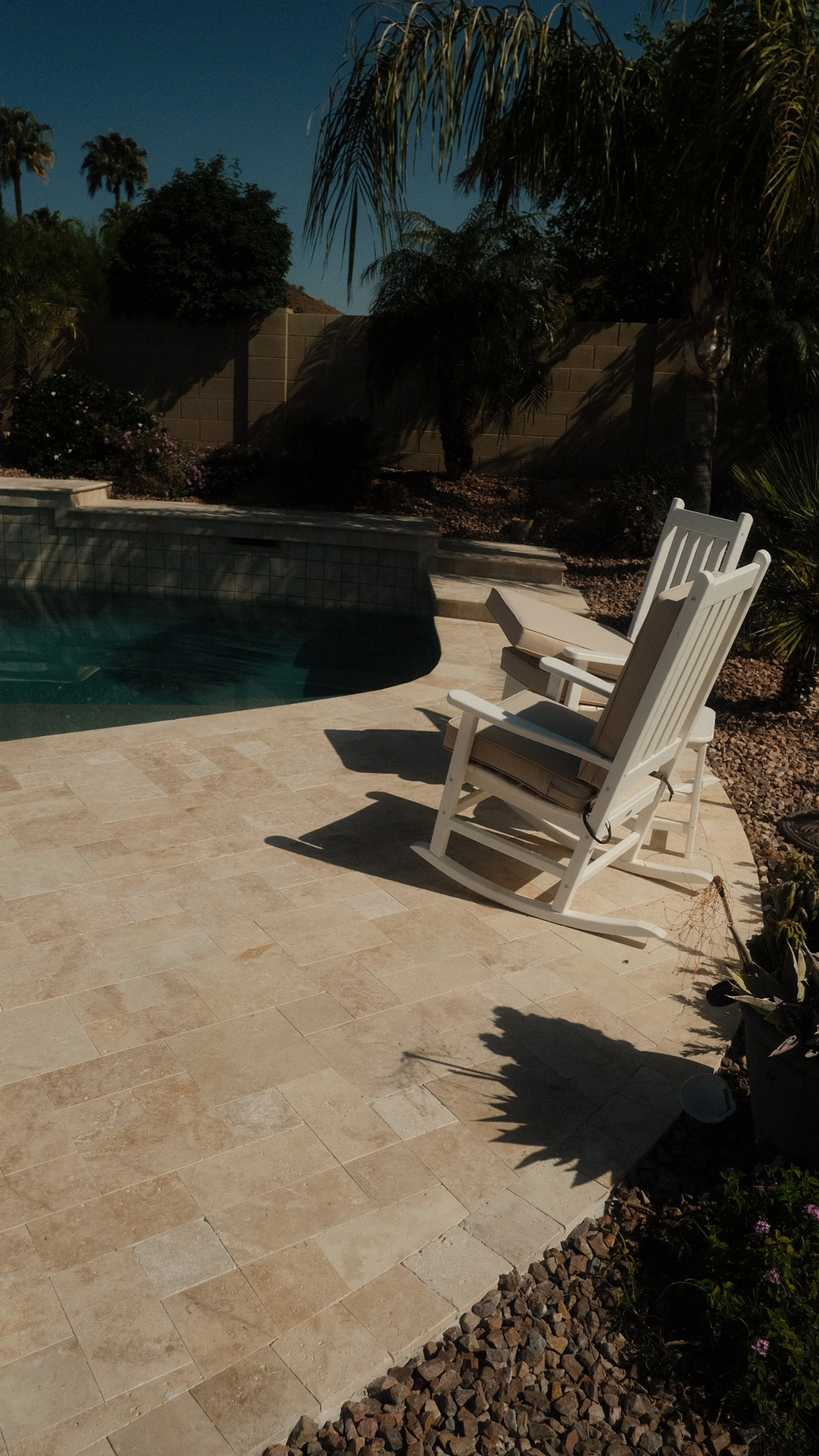 Travertine poolside patio with modern outdoor furniture, showcasing a cool-to-the-touch deck material.