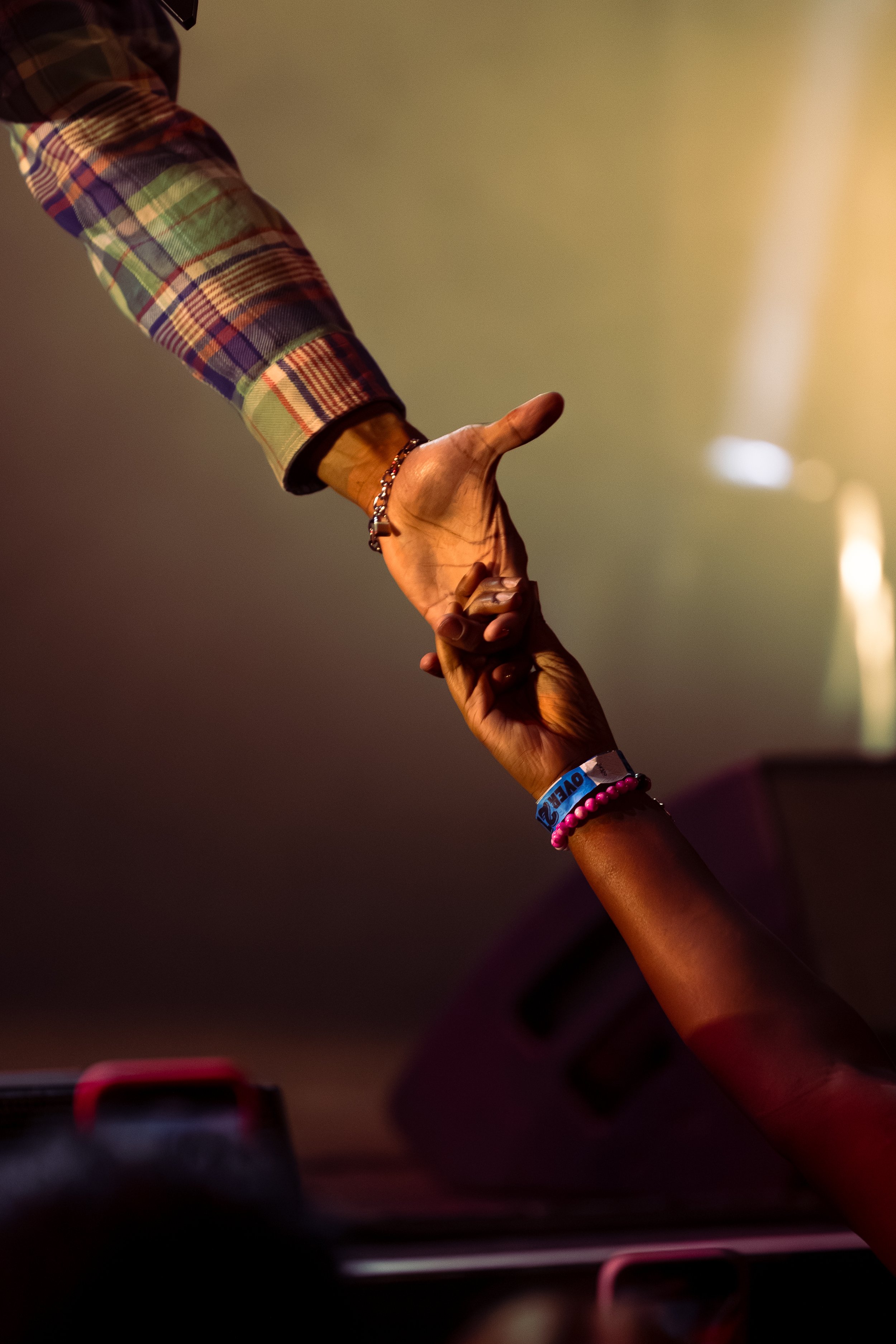 Two hands reaching towards each other, one higher and one lower, in a gesture of connection or help.