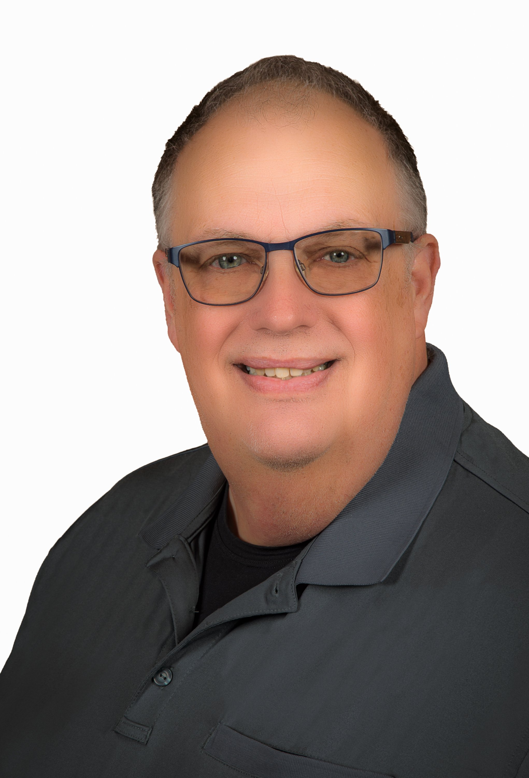 Headshot of a middle-aged man with light skin, short brown hair, glasses, wearing a black collared shirt, smiling against a plain white background.