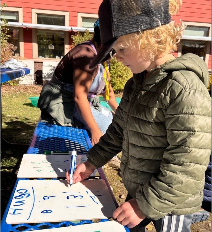 Boy writing numbers on a small whiteboard