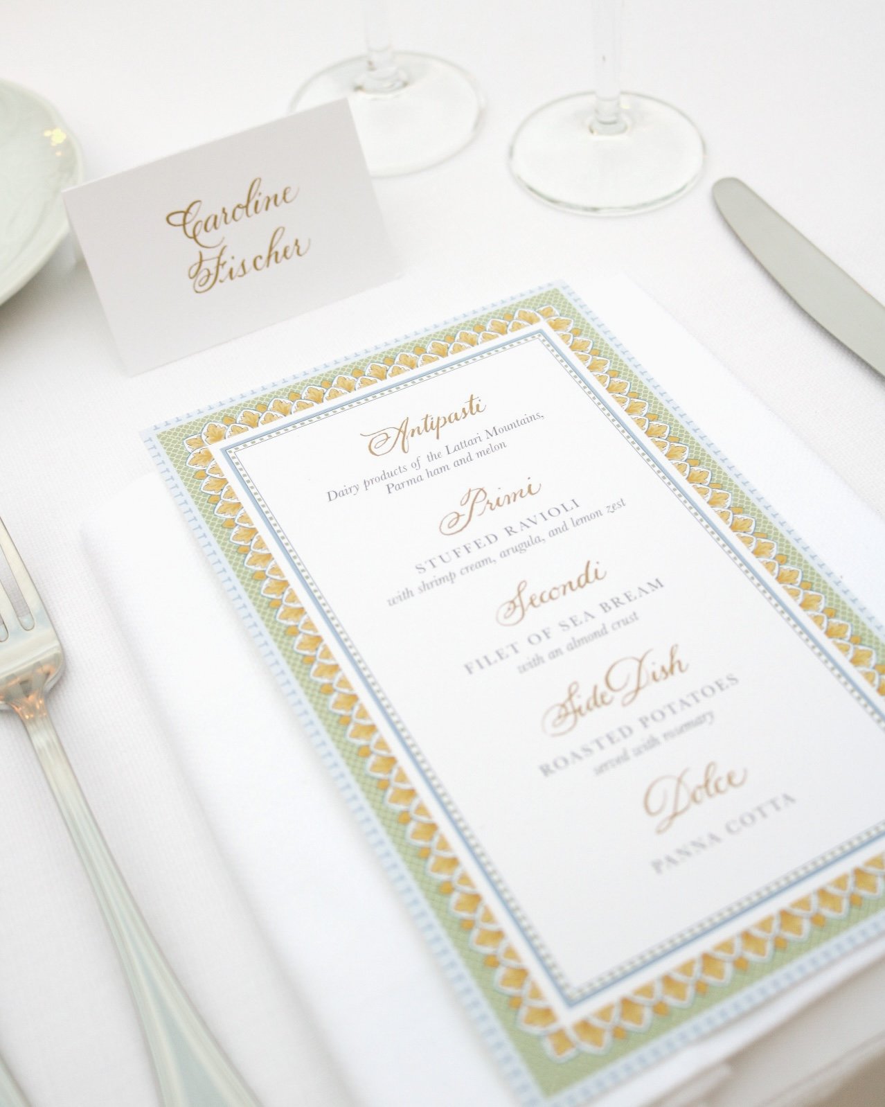 Place setting with a printed menu sitting on a white napkin, a name card, a fork, and a knife at an elegant table.