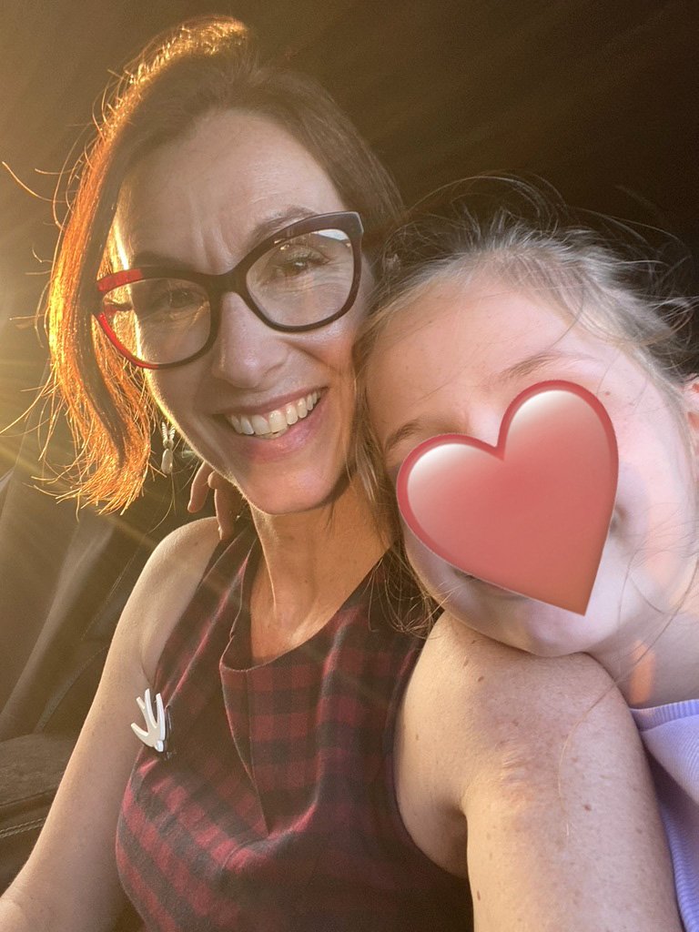 Human Design reader Fiona Lindberg with glasses smiling next to her young daughter whose face is covered with a heart emoji.