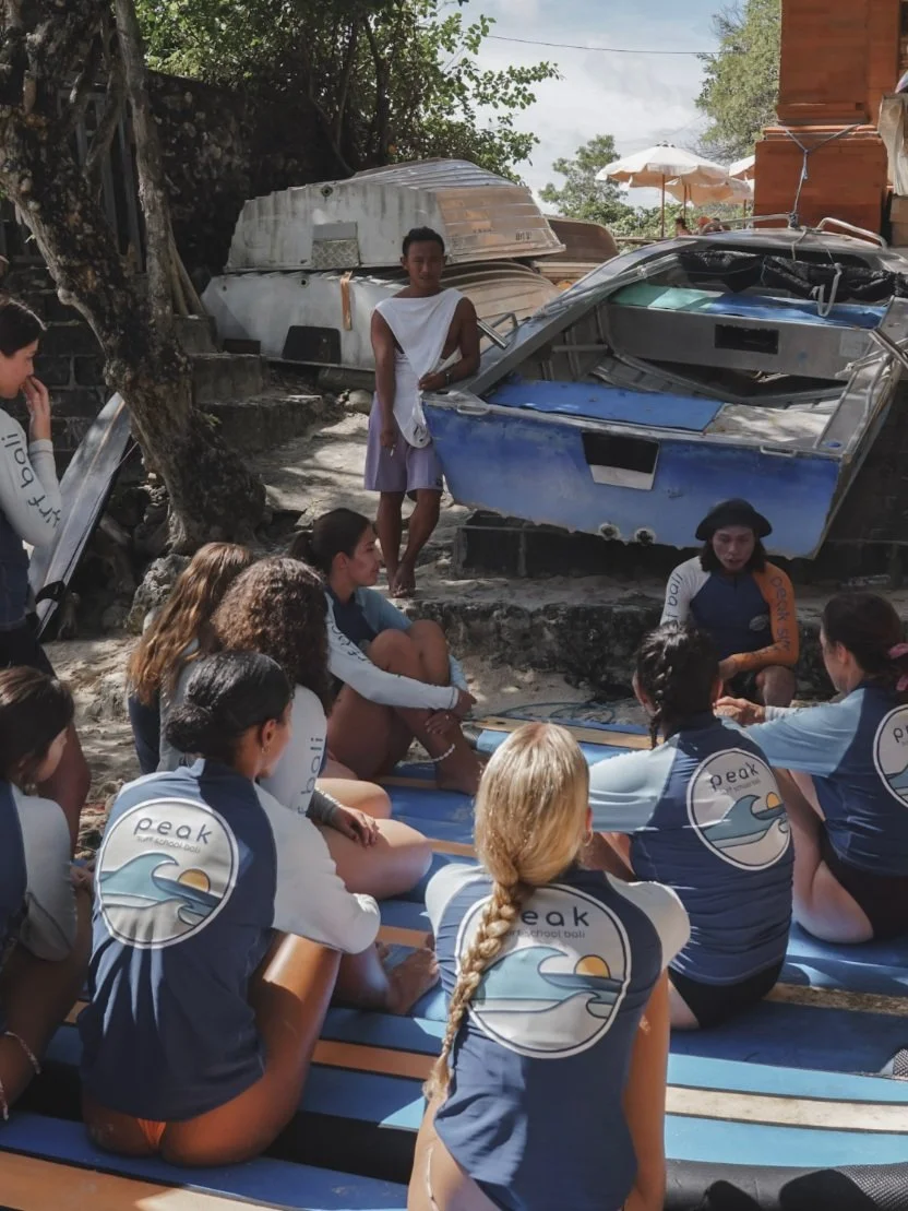 
Peak Surf Bali Students at Padang Padang  surf theory Beach Uluwatu  Yoga Retreat Yoga with Jordan Surfing Peak Surf Bali Surf School high five smiles fun happy joy friendship surfing beautiful beach crystal clear water white sand putting Zinc on fa