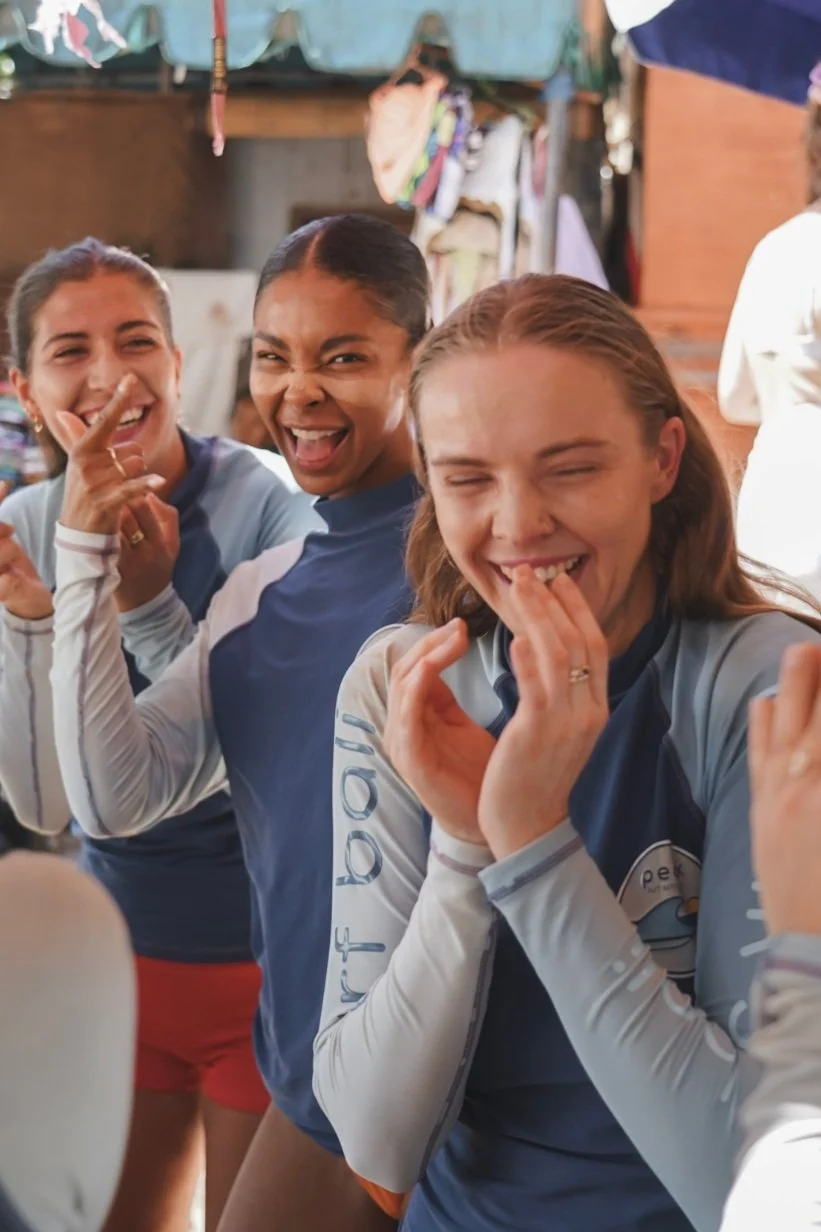 
Peak Surf Bali Students at Padang Padang  surf theory Beach Uluwatu  Yoga Retreat Yoga with Jordan Surfing Peak Surf Bali Surf School high five smiles fun happy joy friendship surfing beautiful beach crystal clear water white sand putting Zinc on fa