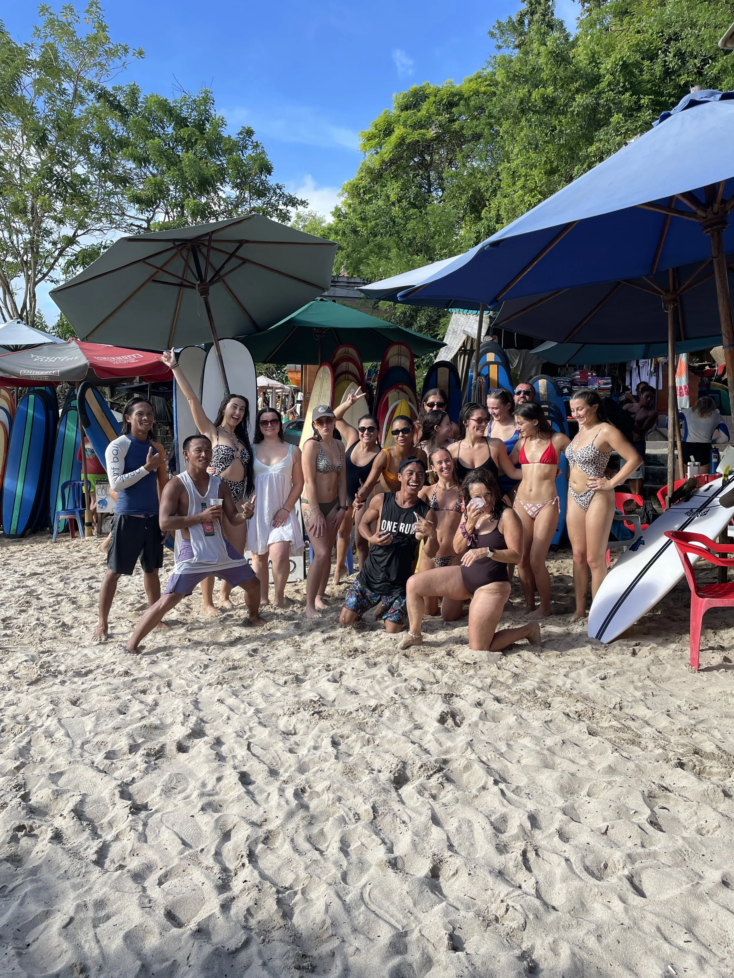 
Peak Surf Bali Students at Padang Padang  surf theory Beach Uluwatu  Yoga Retreat Yoga with Jordan Surfing Peak Surf Bali Surf School high five smiles fun happy joy friendship surfing beautiful beach crystal clear water white sand putting Zinc on fa