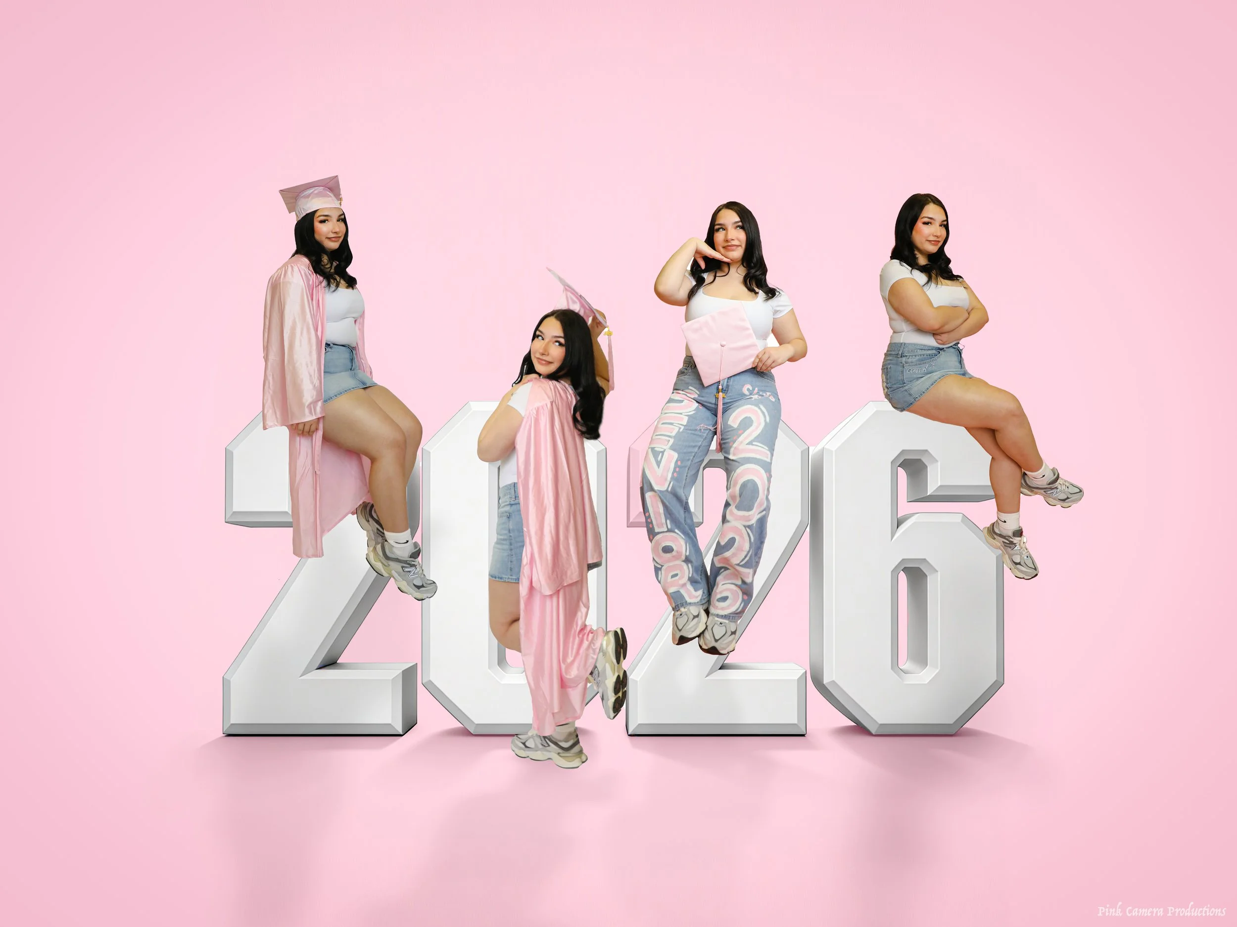 Four women in casual outfits and pink graduation caps and gowns sitting on large 3D block numbers spelling '2026' against a pink background.