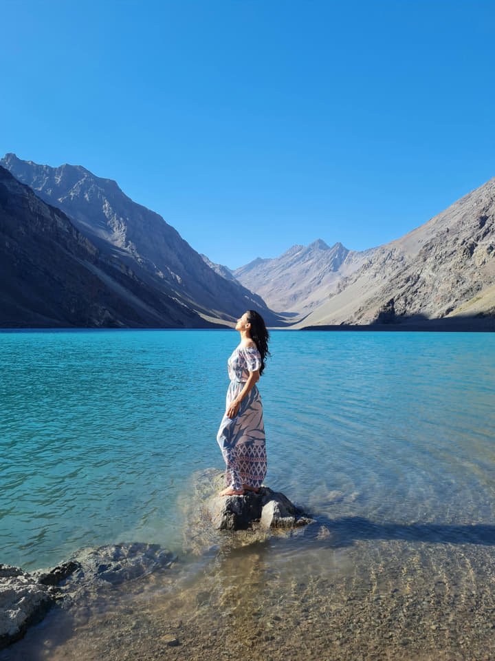 A girl standing in the water with a mountain view