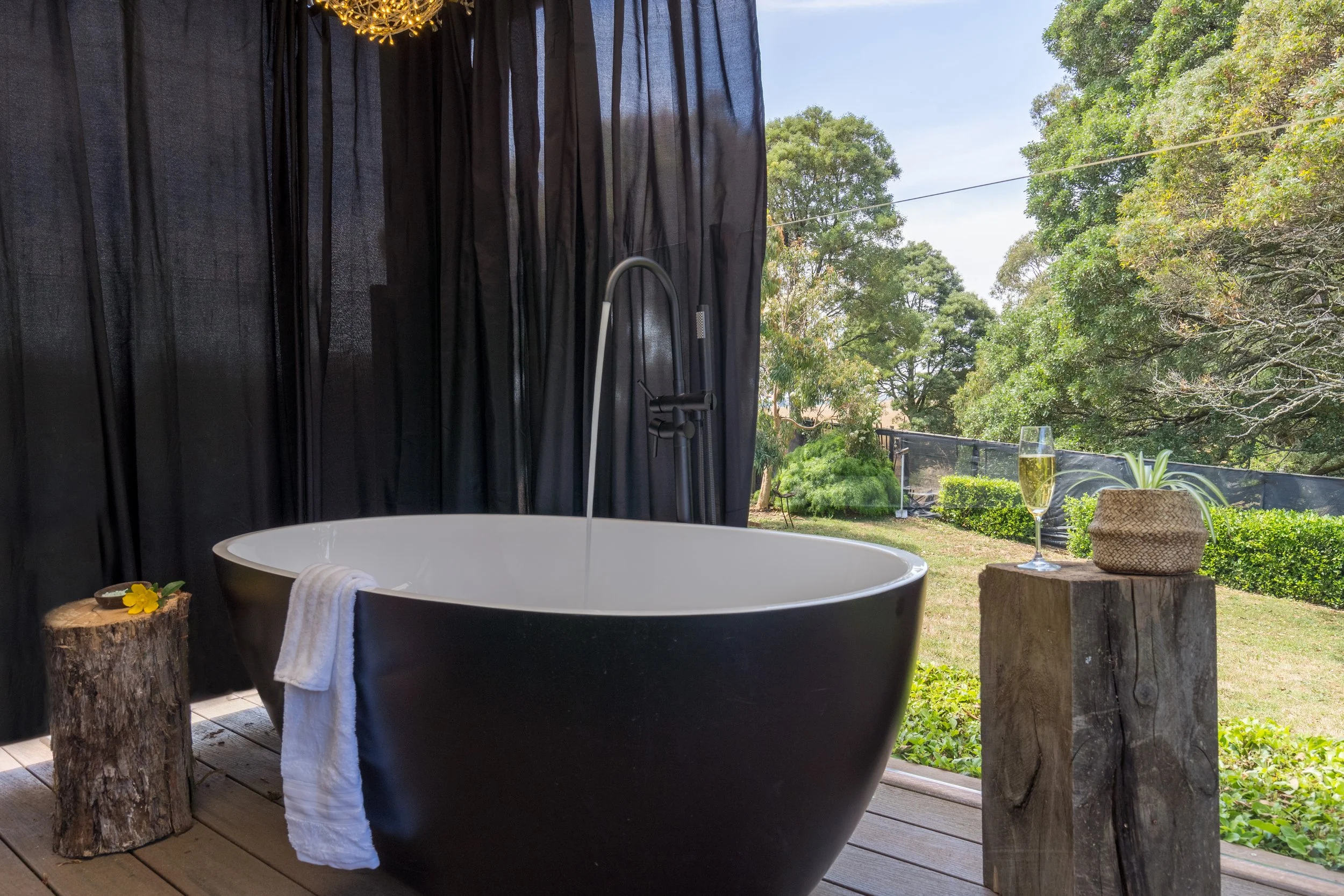 Black freestanding outdoor bath for two on a private deck at a couples retreat holiday home