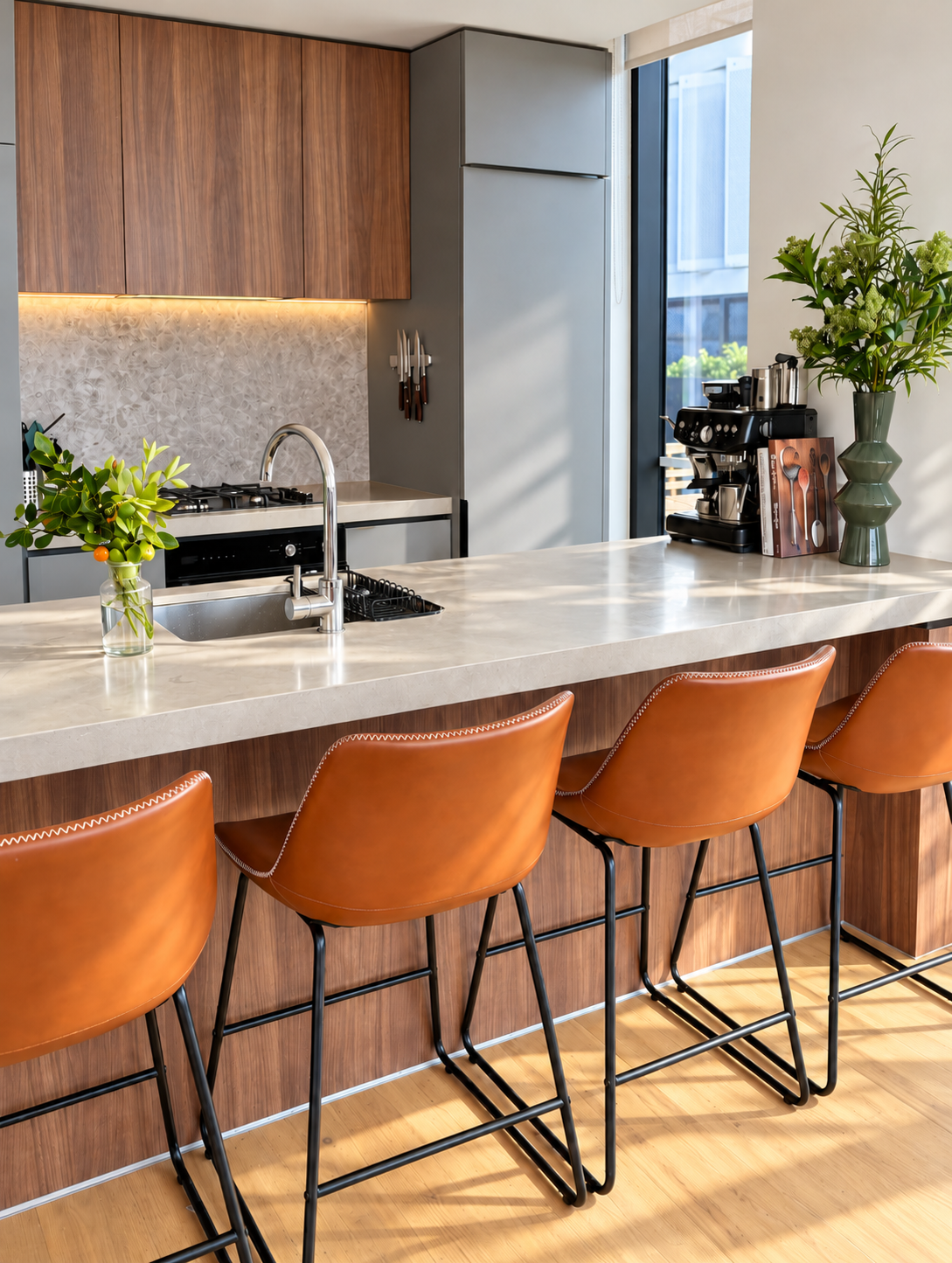 Styled kitchen island with tan leather bar stools, fresh greenery and a coffee station in a two-bedroom rental apartment