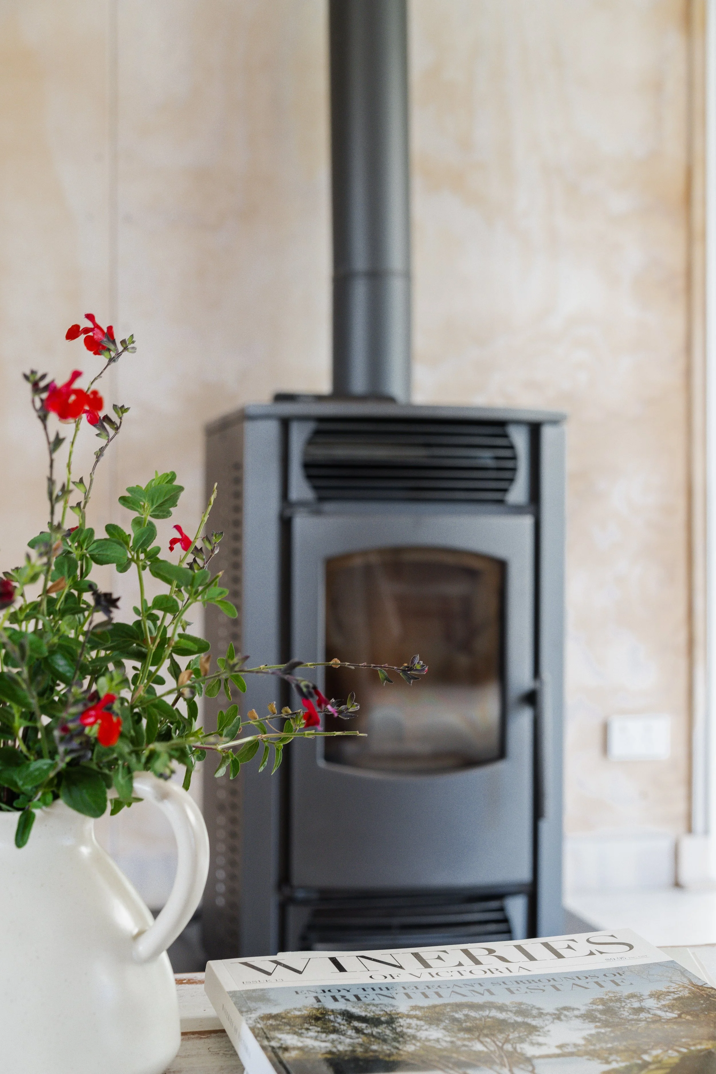 Wood heater in a country holiday home styled with a jug of fresh flowers and local magazines