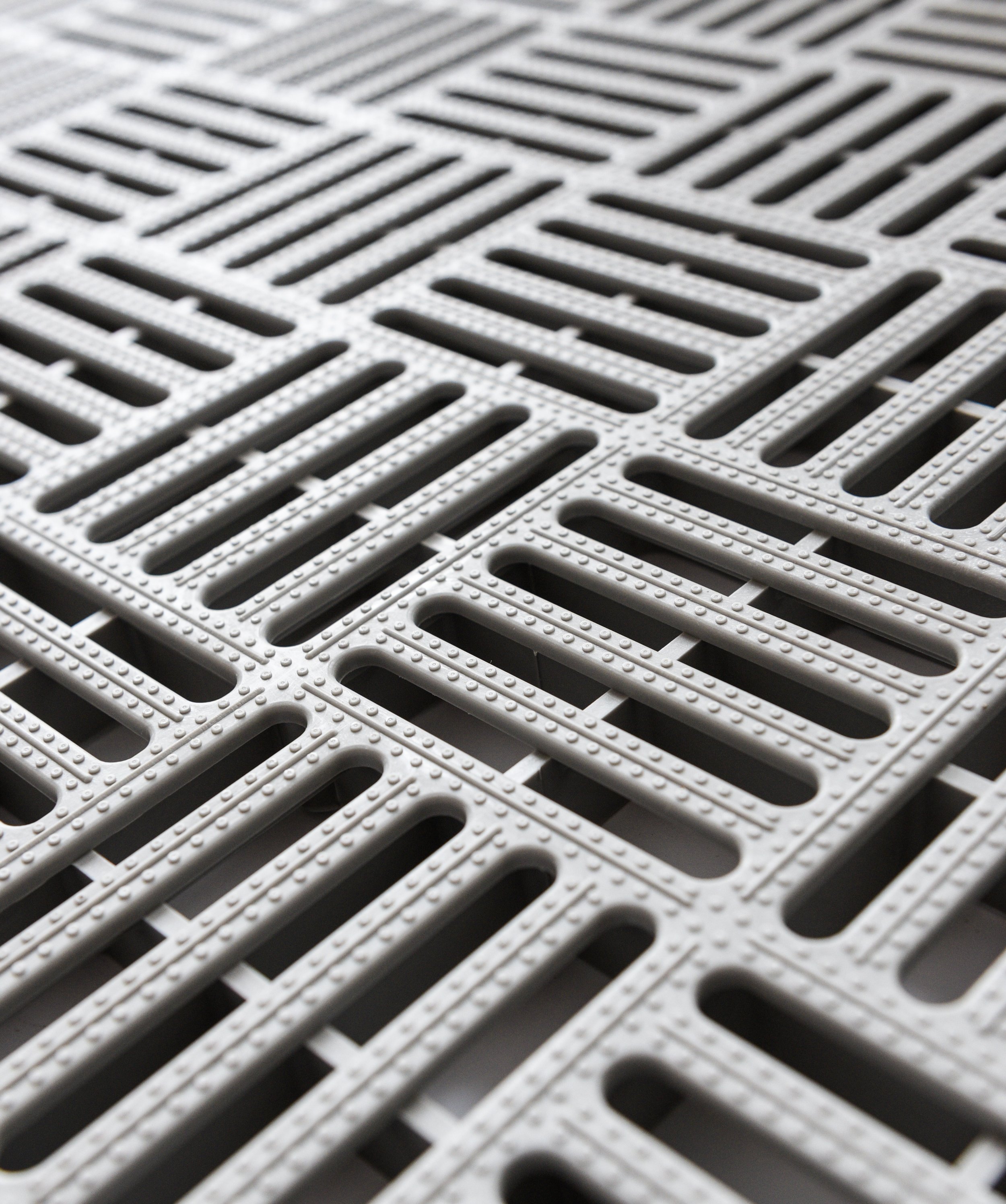 Close-up of gray metal drainage grates with rectangular slots and textured surface.