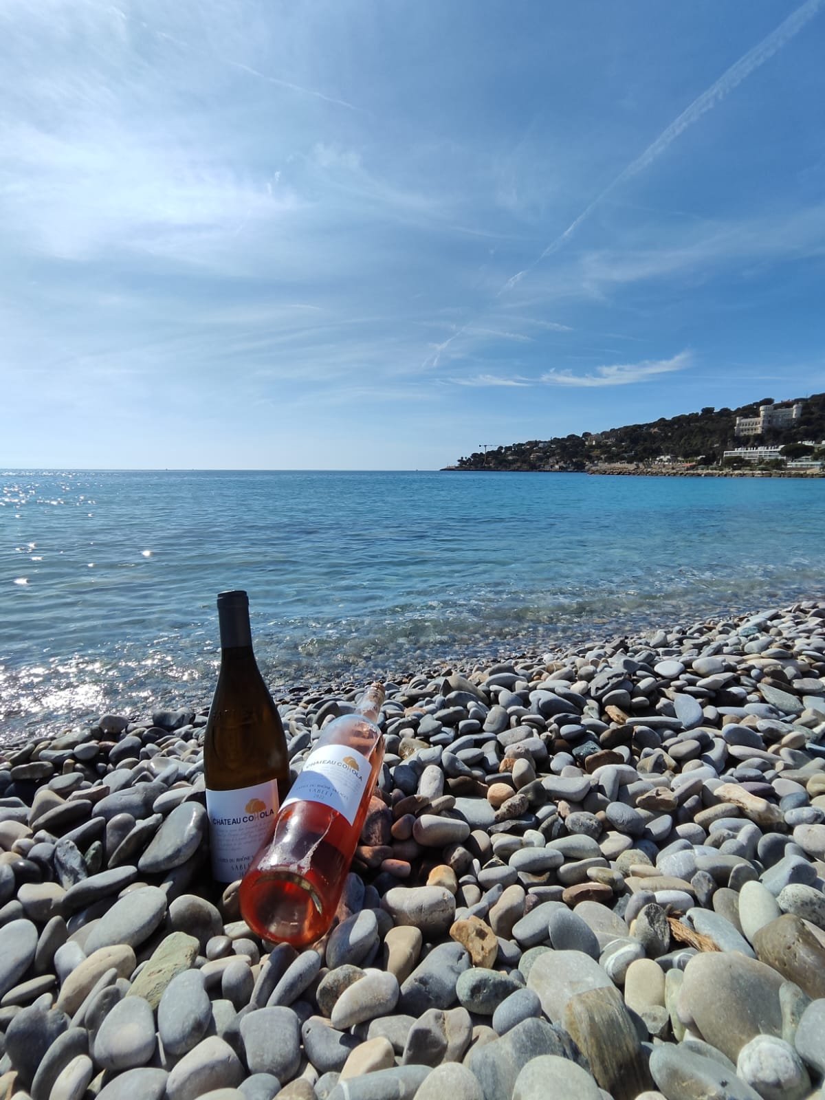 2 bouteilles sur une plage de galets devant la mer