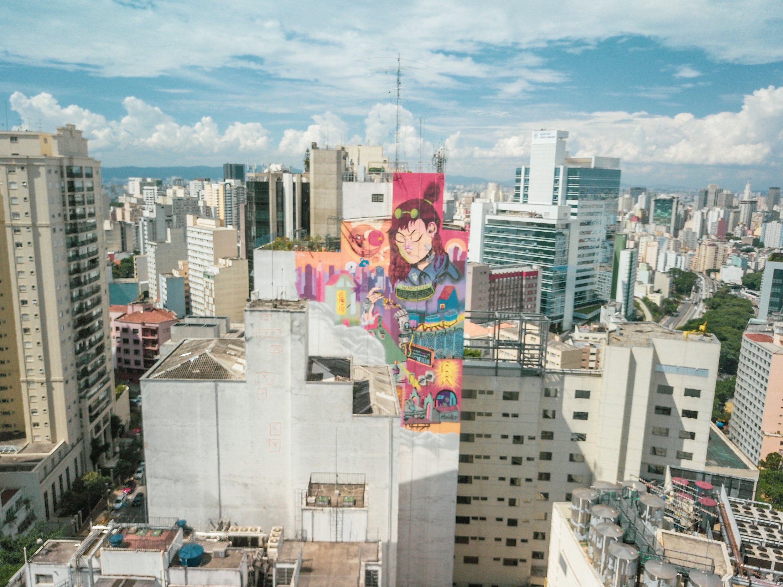 Vista aérea de São Paulo com um mural colorido em um edifício no centro da imagem.