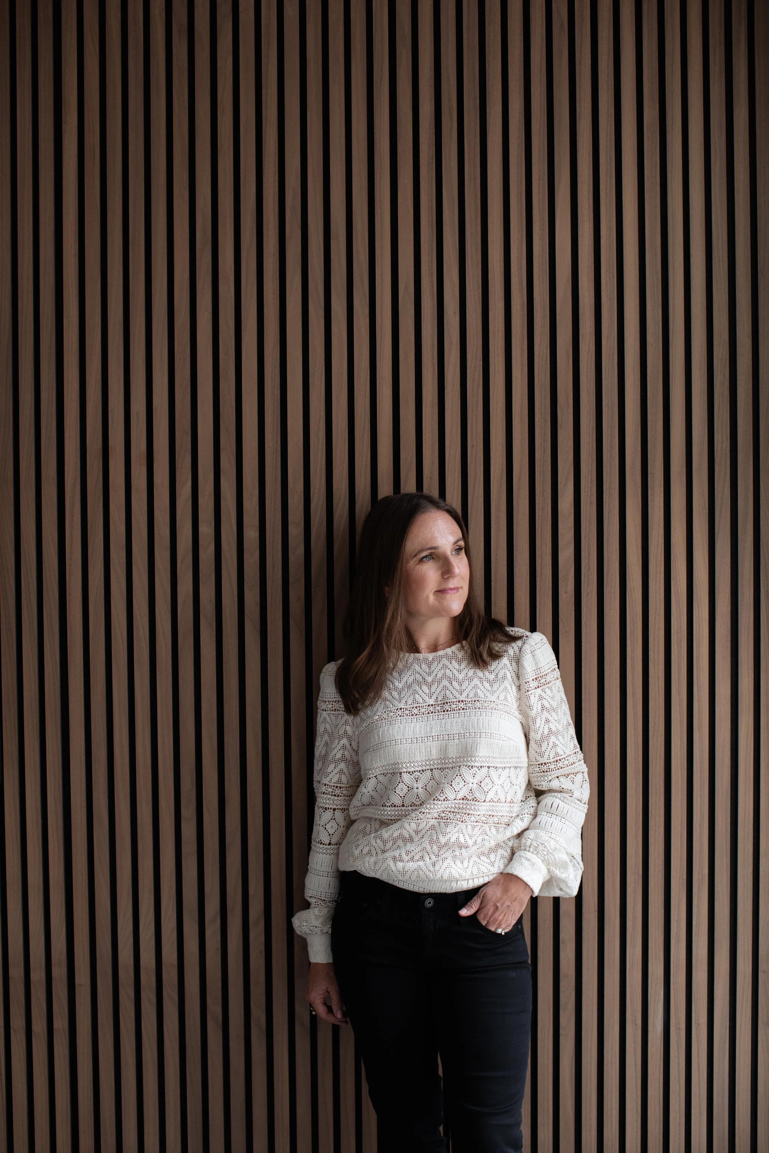 stylish-business-woman-leaning-panelling-wall-brown-gold-cream-relaxed