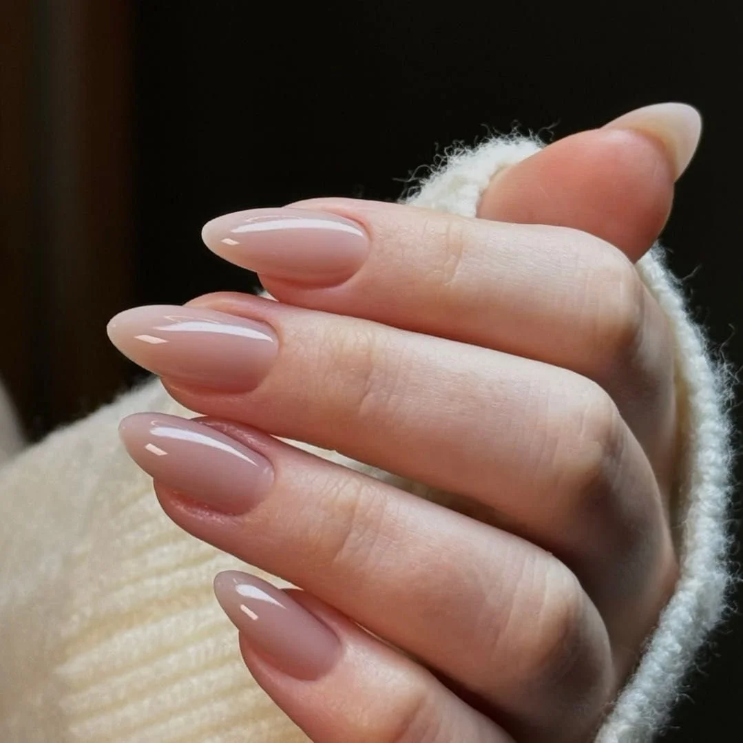 Close-up of a hand with manicured nails, holding onto a fluffy, cream-colored sweater sleeve.