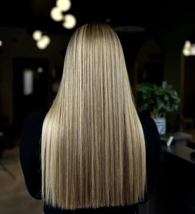 Back of a woman with long straight blonde hair inside a salon