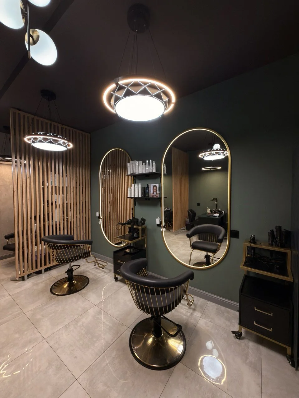 Interior of a modern hair salon with barber chairs, mirrors with gold frames, and contemporary lighting fixtures.