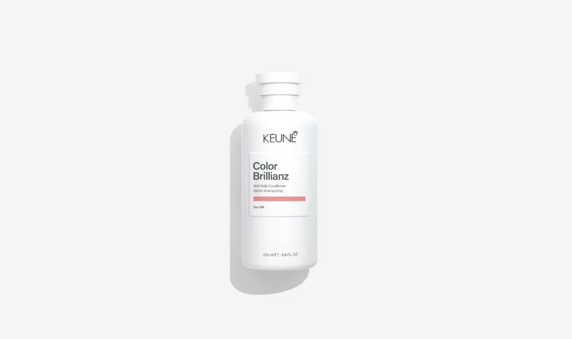 A white bottle of KEUNE Color Brilliance anti-fade conditioner with a pink stripe on the label, placed against a white background.
