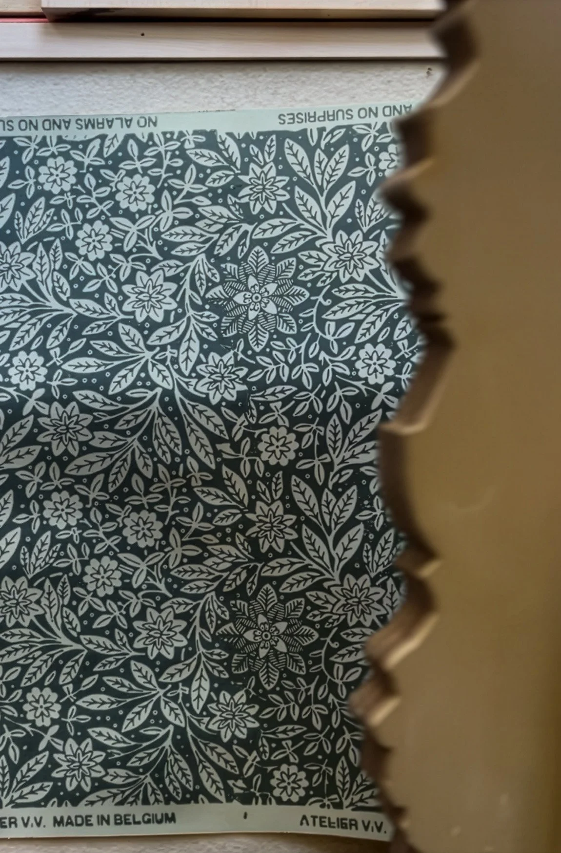 Close-up of a sheet of patterned wrapping paper with floral design, with part of a brown corrugated cardboard box visible on the right side.