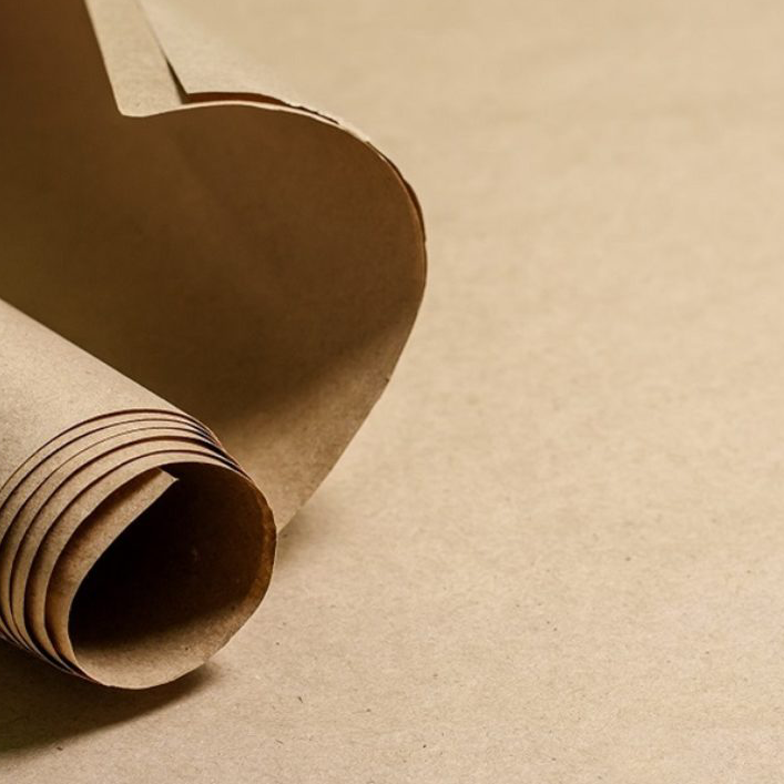 Close-up of a partially curled and rolled brown paper sheet on a flat surface.