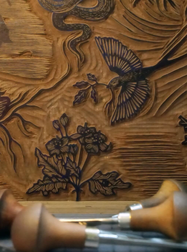 Wood carving depicting a bird, flowers, and leaves.