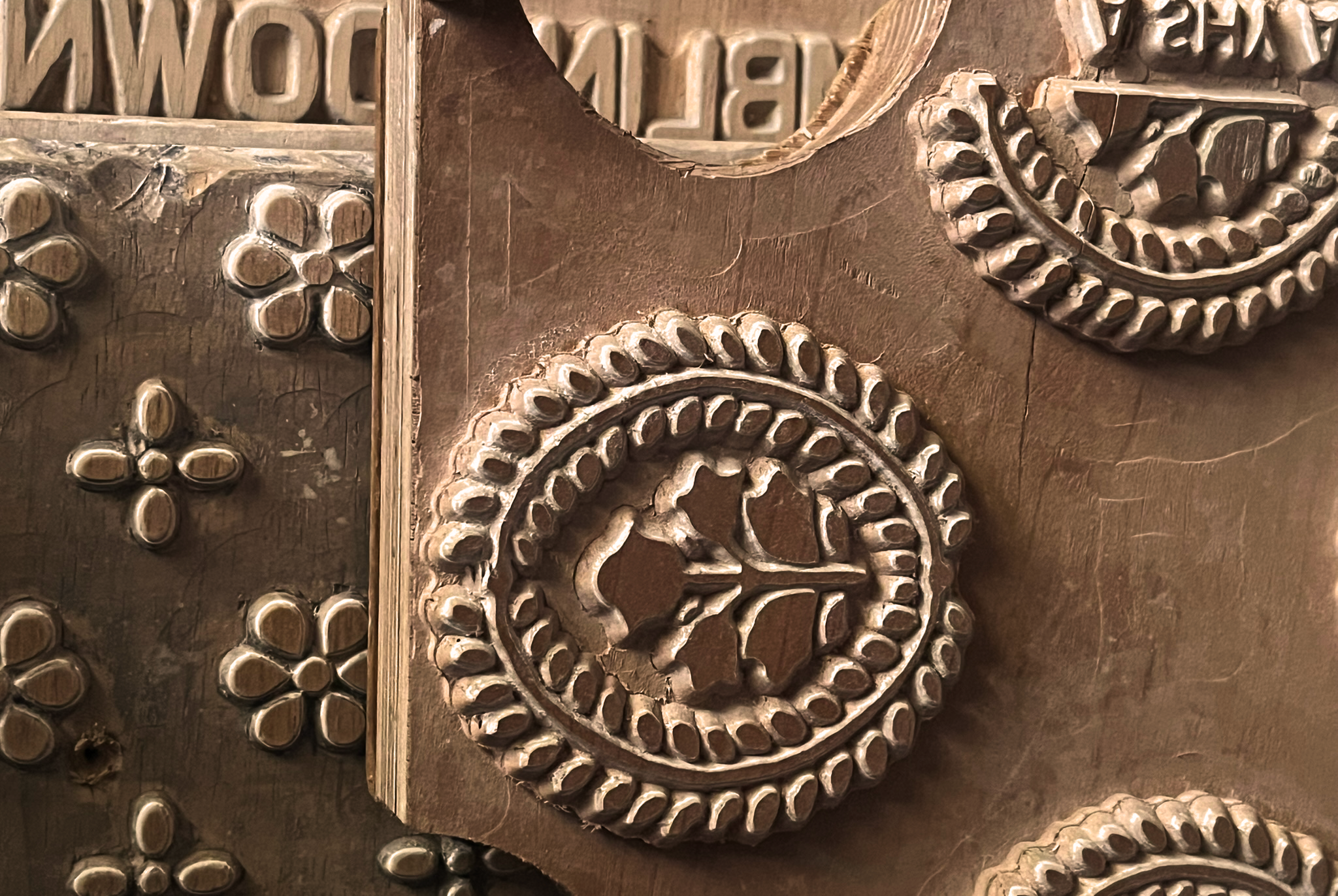 Close-up of a metal sculpture or decorative piece with detailed circular and floral patterns, featuring a brown and silver color scheme.