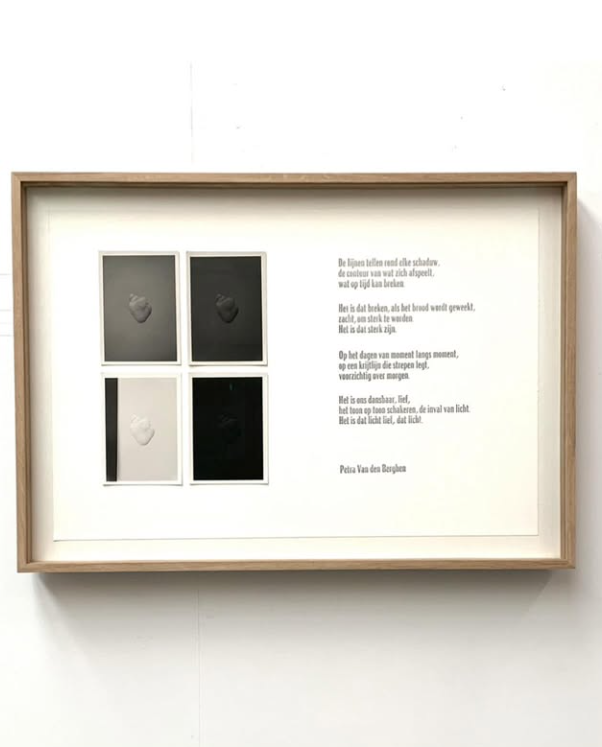 A framed artwork featuring four small square photographs or prints arranged in a 2x2 grid, each displaying a raised or textured shape, along with a poem in Dutch on the right side.