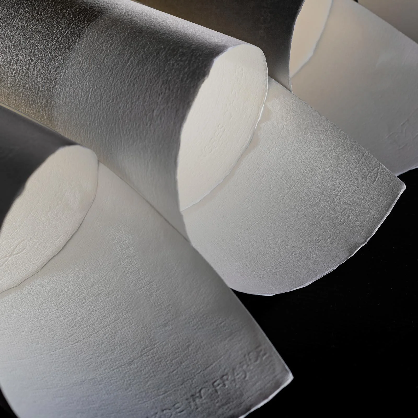Close-up of several white and gray sheets of paper or foam with textured surfaces, some curled or folded.