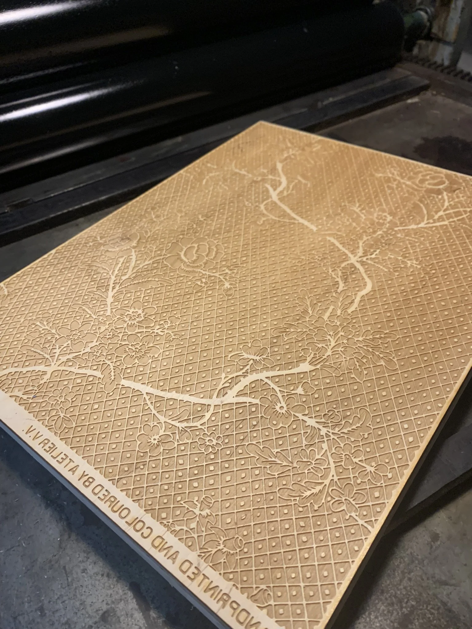 A detailed embossed rubber or silicone mat with floral patterns and a grid background, placed on a wheelchair armrest.
