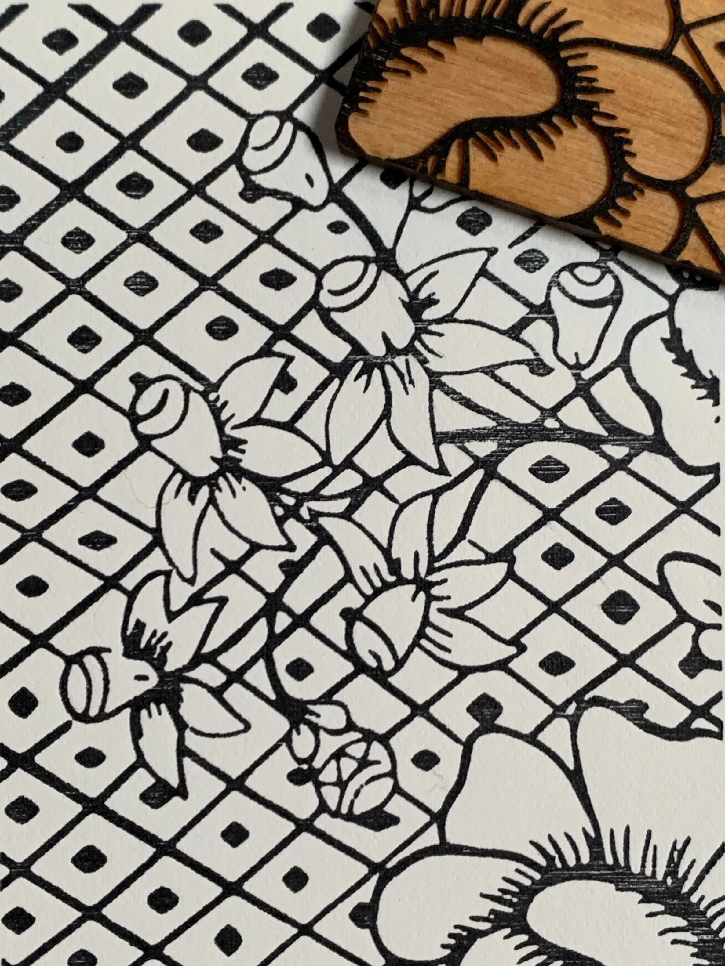 Black and white line drawing of daffodil flowers, with a wooden stamp featuring a daffodil design placed partially on the paper.