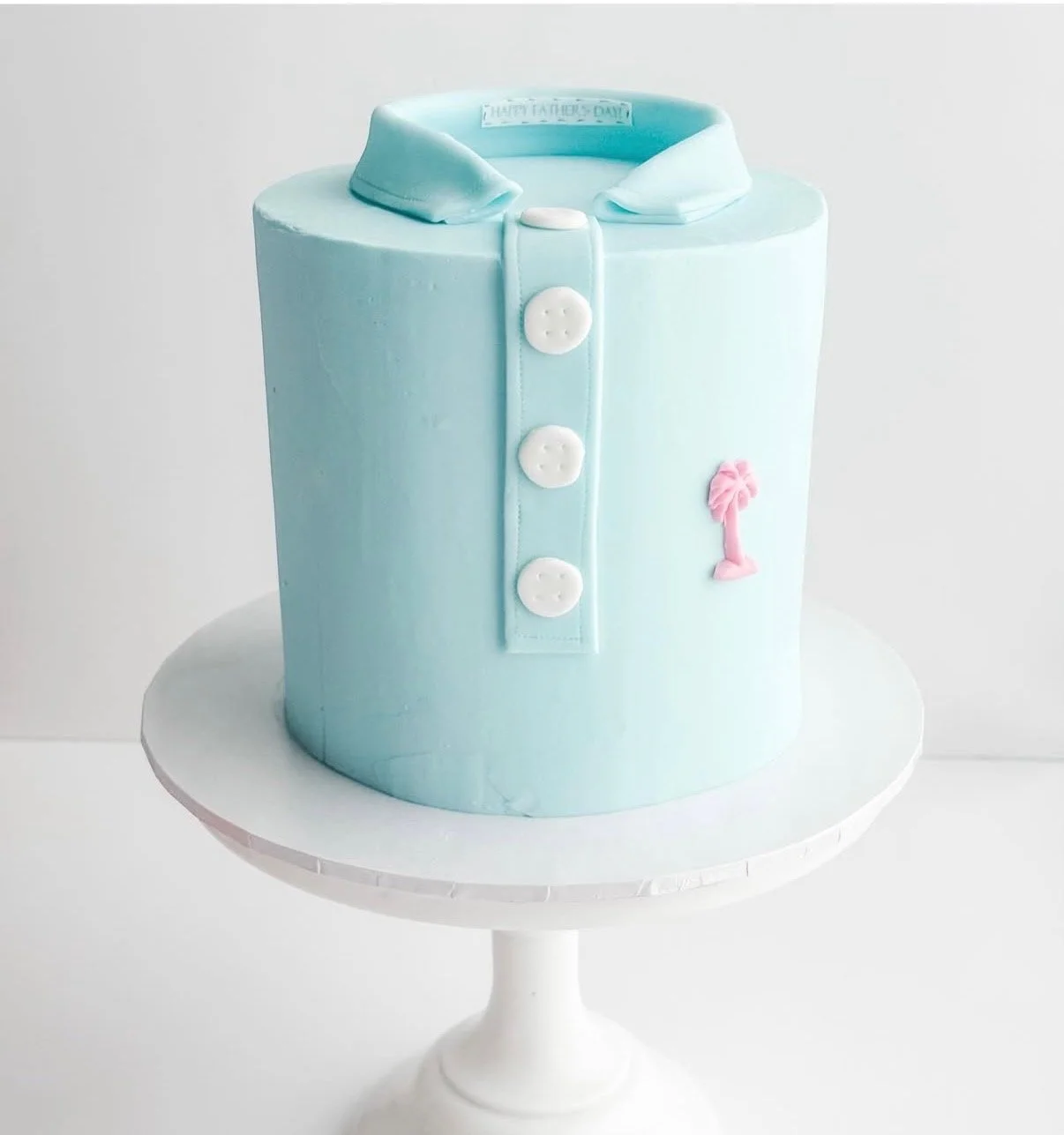 cake with blue icing and decorated as a polo shirt with buttons and a palm tree logo